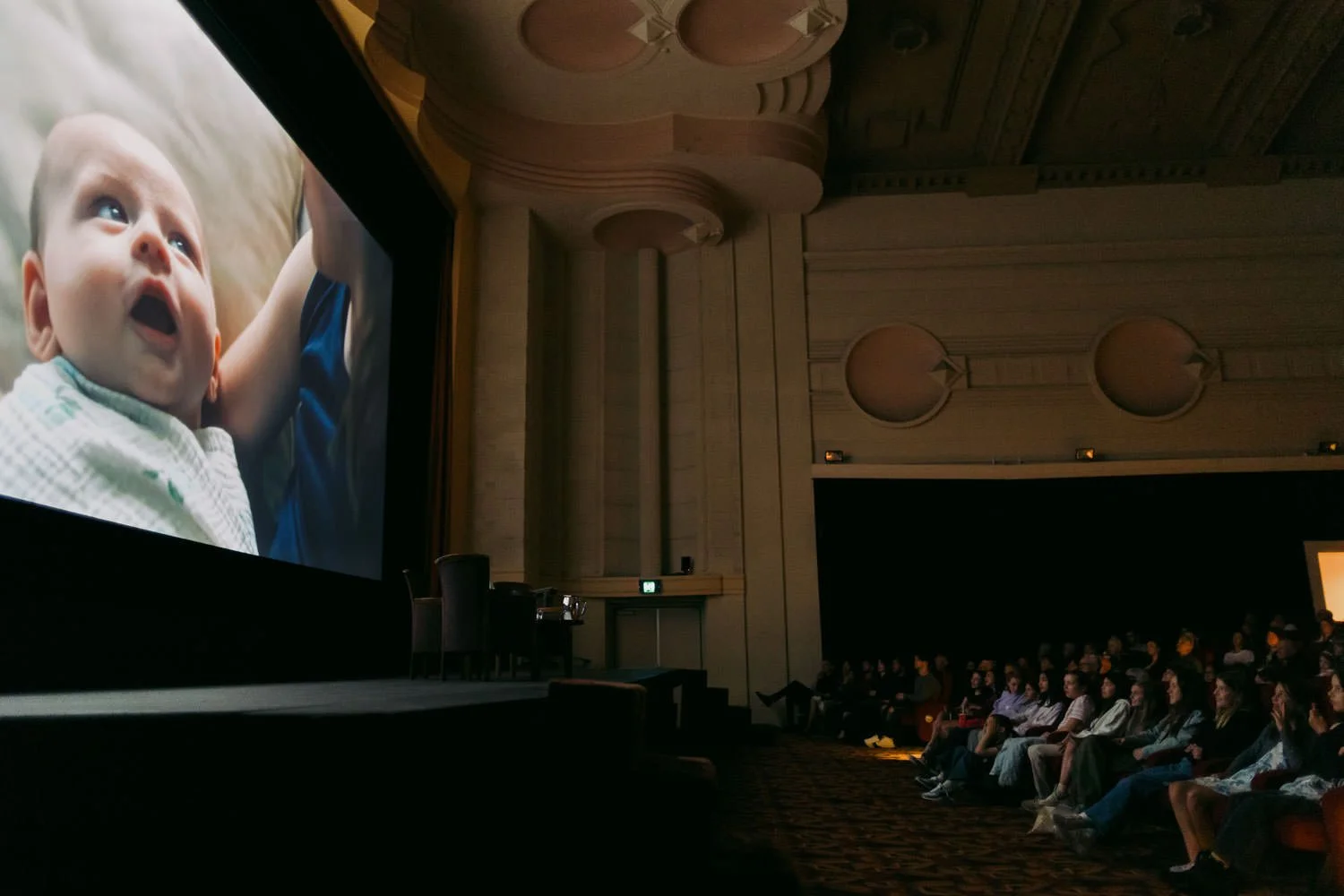 Screening of Things Will Be Different at Palace Cinemas, with a seated audience watching a close-up of a surprised baby on the cinema screen.