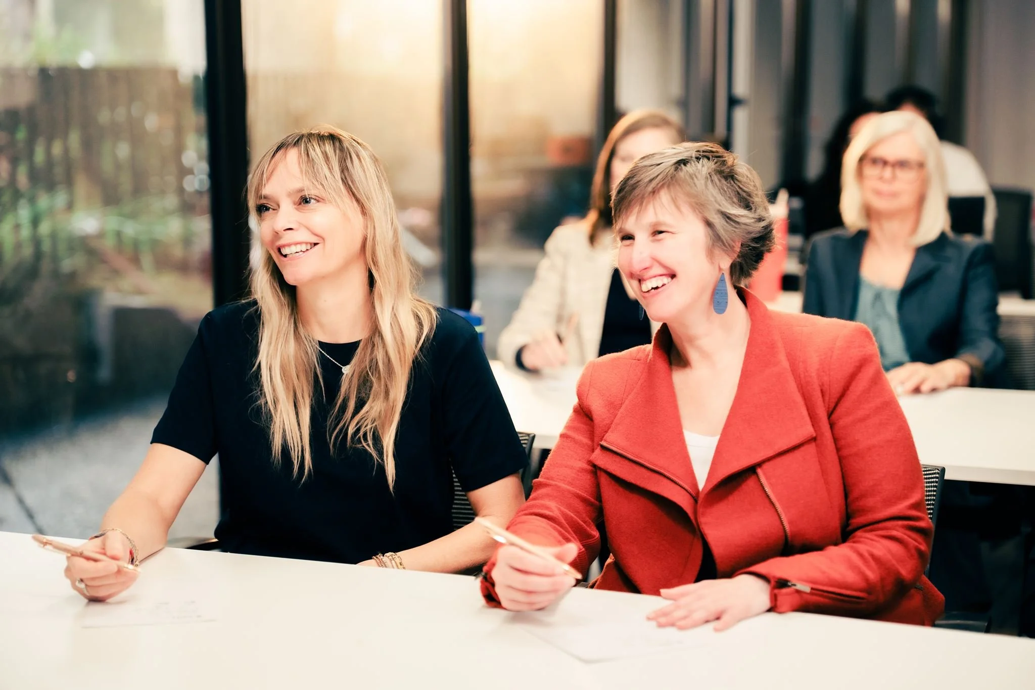 Women in class at Mary Andrews College, smiling and taking part in a group discussion.