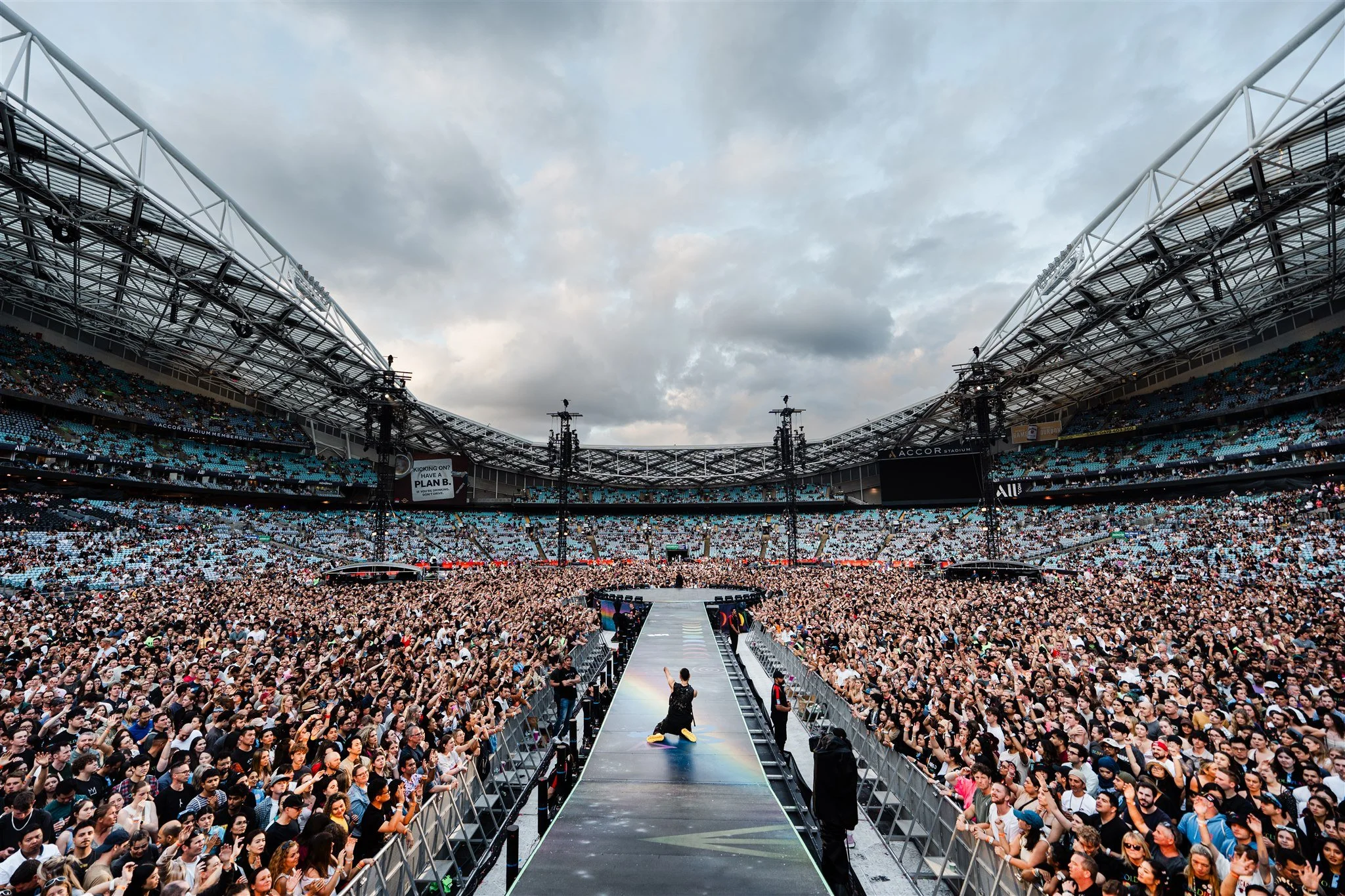 Emmanuel Kelly performing in support of Coldplay at Accor Stadium in Sydney, in front of a packed stadium crowd.