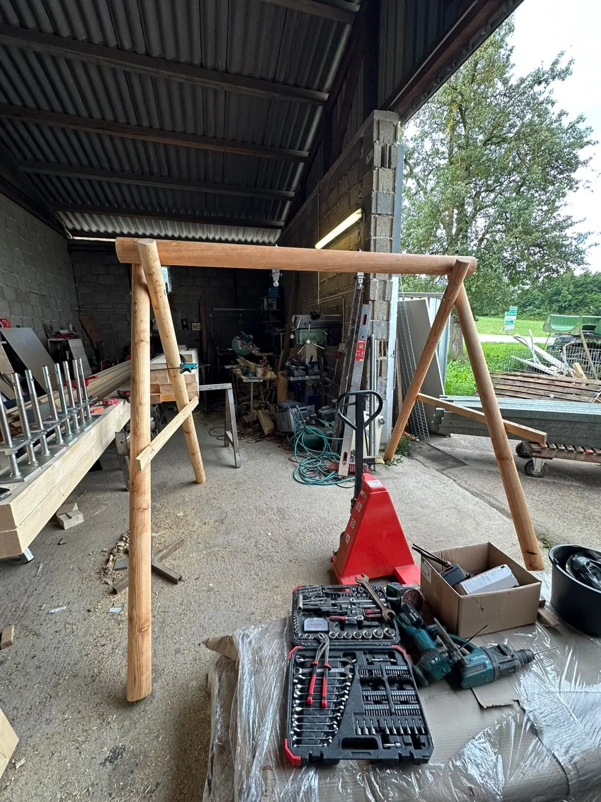 Werkstatt mit Holzbalken, Werkzeugen, Elektrowerkzeugen, Schraubenziehern, und Maschinen, die für den Bau eines Holzrahmens oder einer Schaukel verwendet werden.