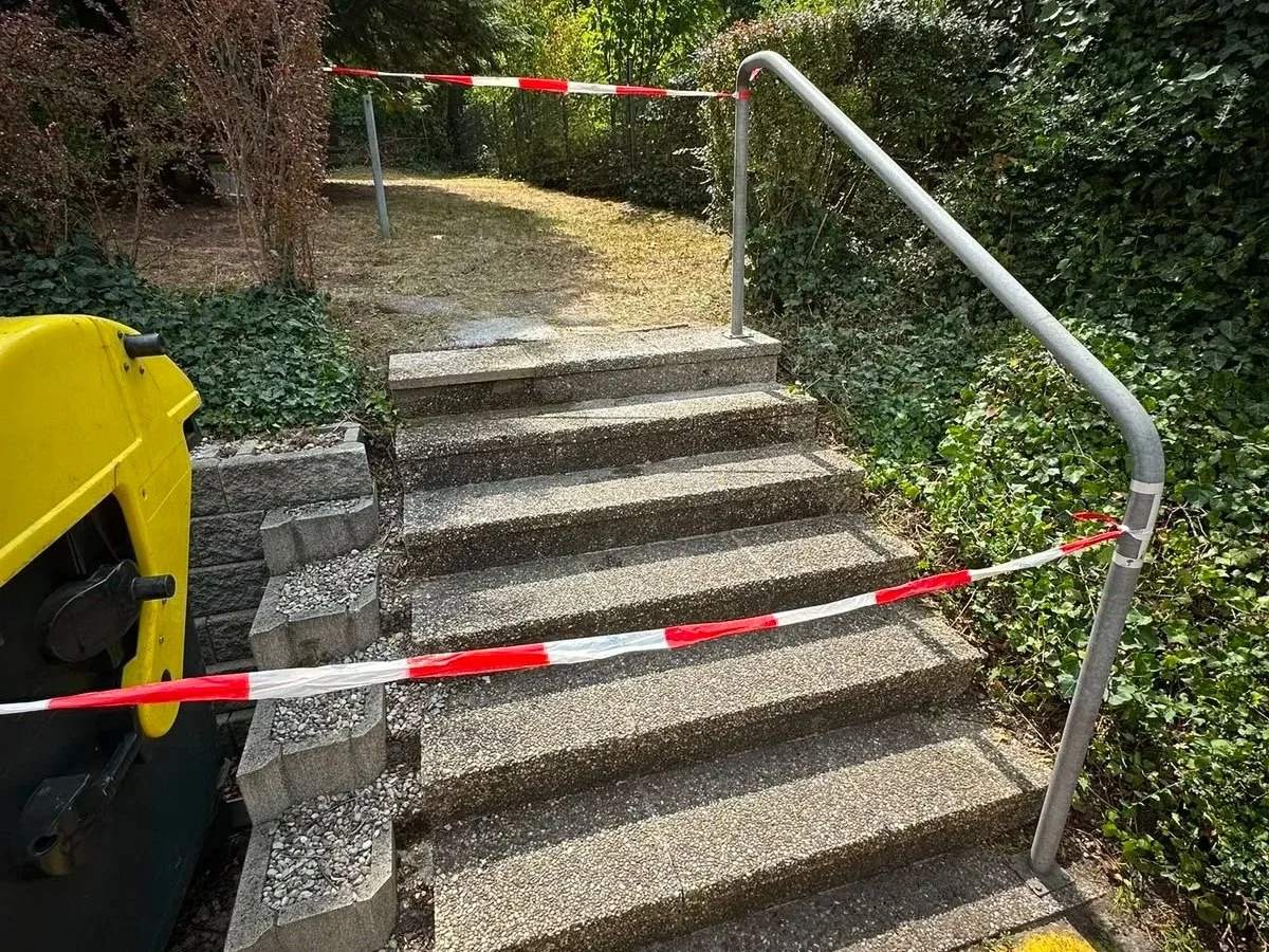 Der Zugang zu den Treppen ist abgesperrt mit rotem und weißem Flatterband und Absperrung. Es gibt einen Mülleimer auf der linken Seite.
