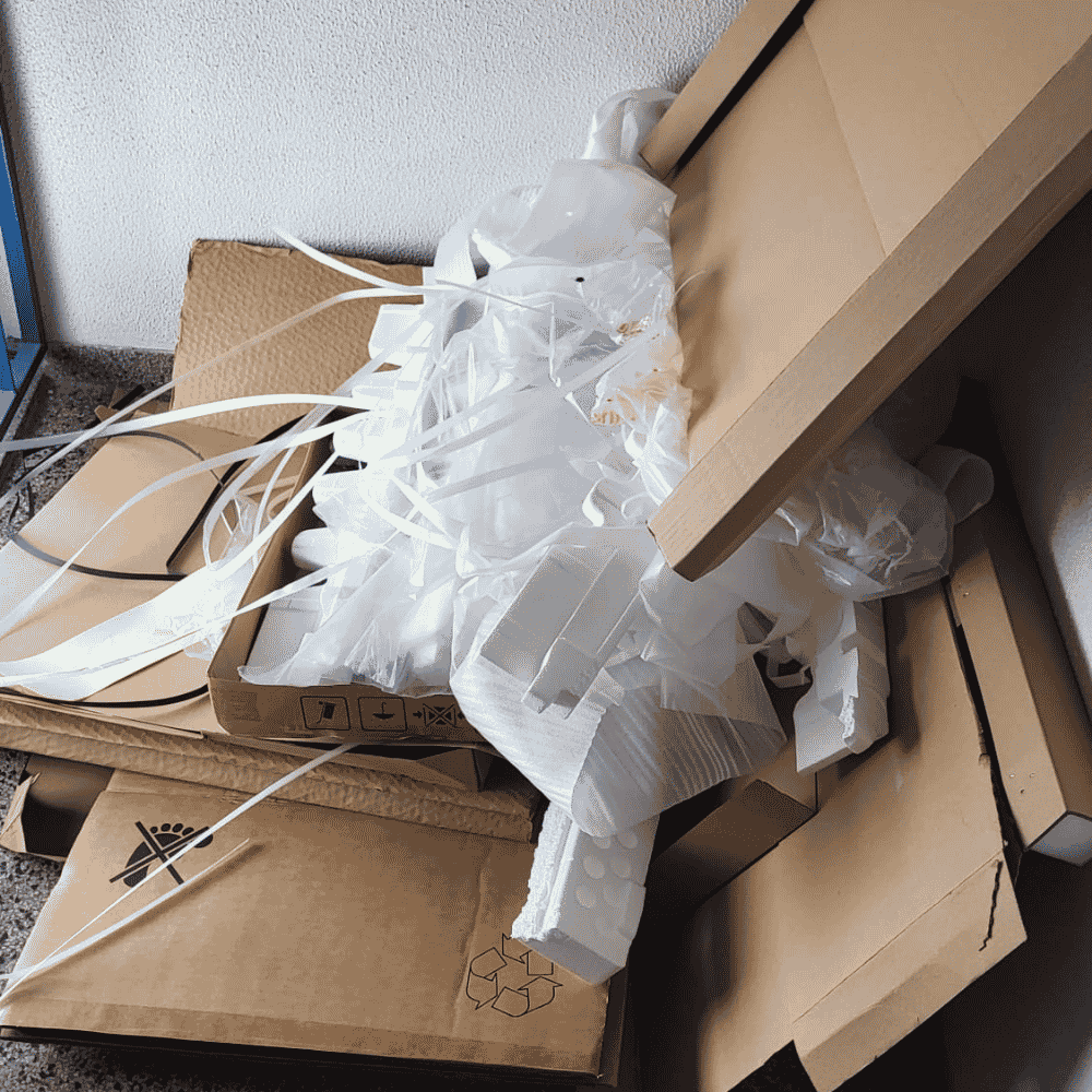 Offene Verpackung mit weißen Luftballonbändern, Verpackungsmaterialien und Kartons auf einem Tisch.
