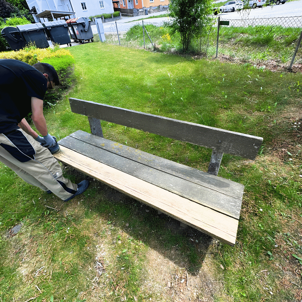 Jemand repariert eine Holzbank im Garten.