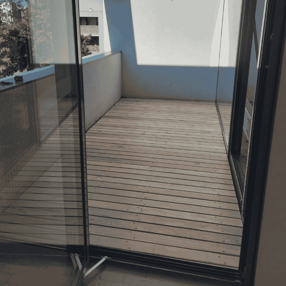 Leerer Balkon mit Holzfußboden und Glas-Schiebevorhängen
