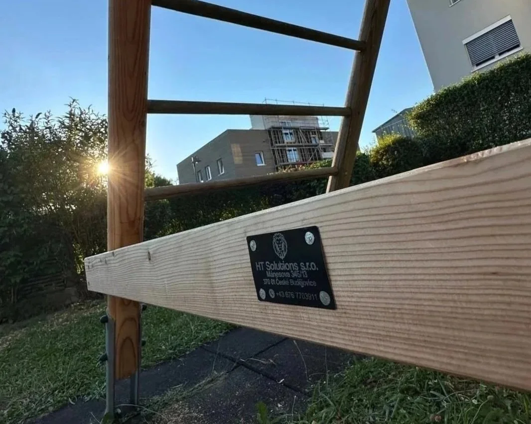 Ein Holzrahmen im Garten bei Sonnenuntergang mit Blick auf moderne Häuser im Hintergrund.
