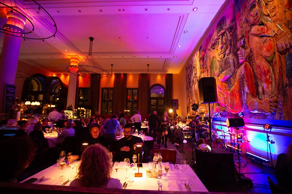 Ein festliches Abendessen in einem eleganten Saal mit Live-Musik und Dekorationen in warmen Farben.