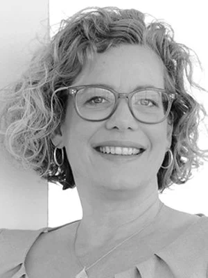 Porträt einer lachenden Frau mit curly Haaren und Brille