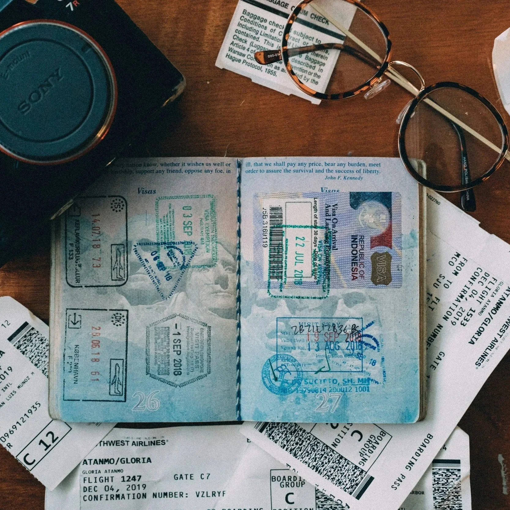 Travel documents, including a passport with visas and transportation tickets, on a wooden surface. The documents include airline boarding passes from Southwest Airlines and a boarding pass for flight 1247 at gate C7, dated December 4, 2019.