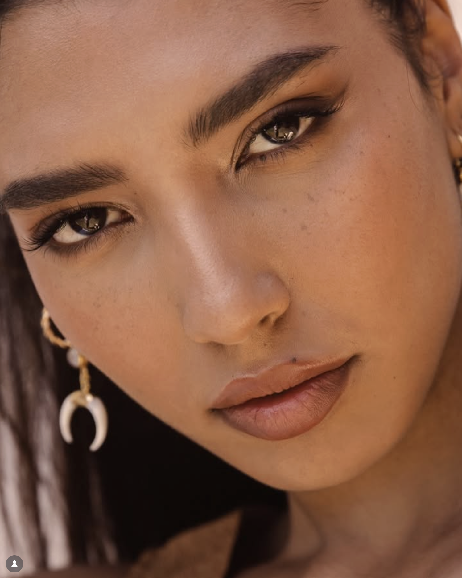 Close-up of a woman's face highlighting her eye, eyebrow, lips, and part of her earrings.