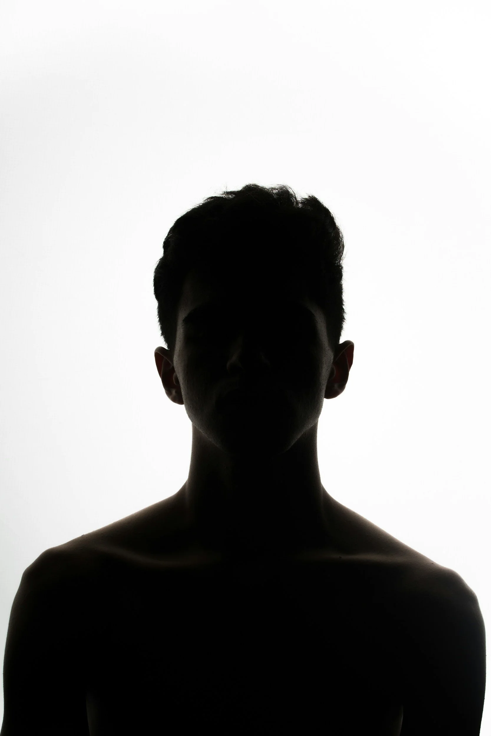 Silhouette of a shirtless man with curly hair against a white background.