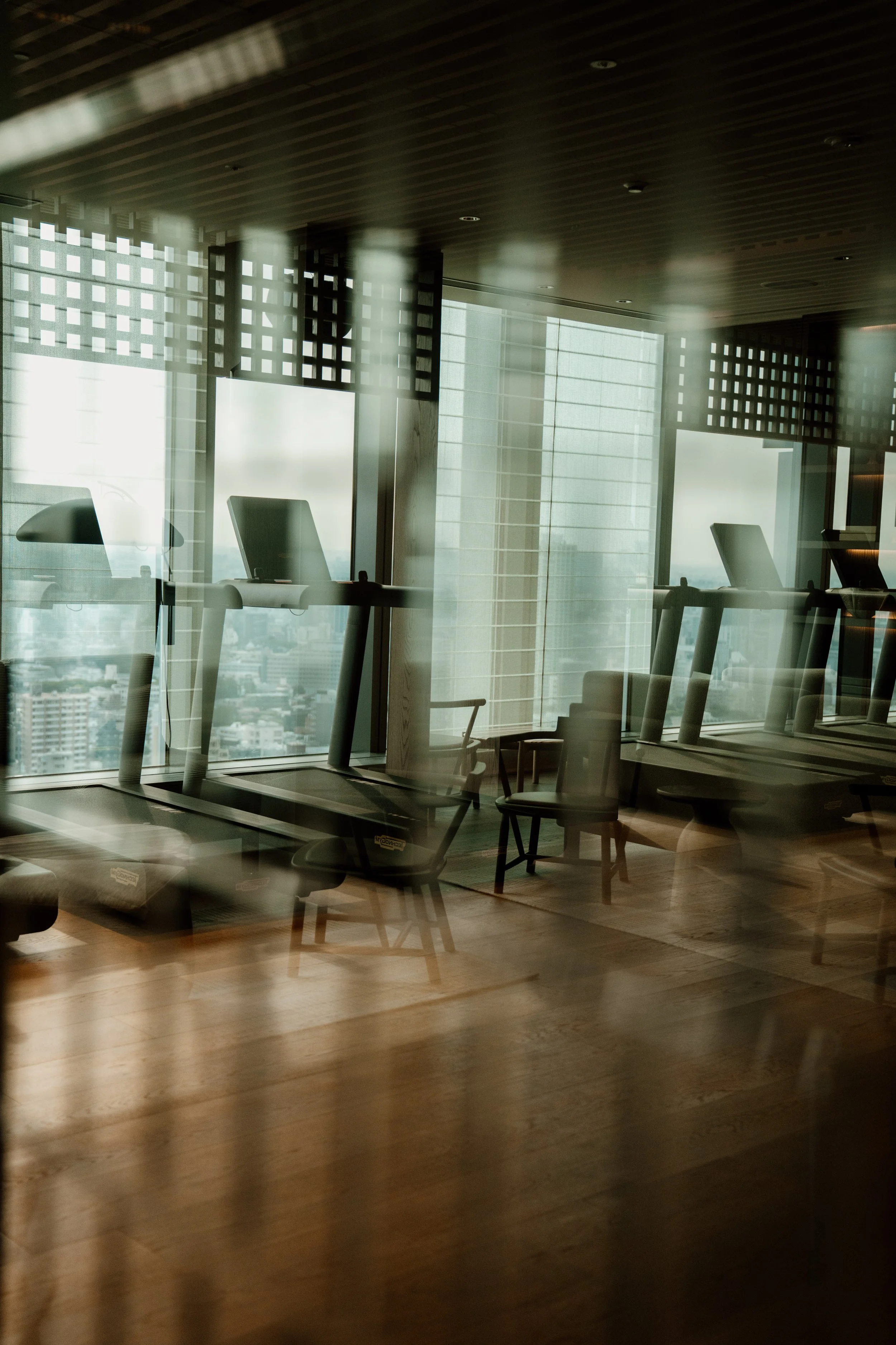 Interior view of an office with several chairs and a large window with cityscape view, seen through a glass wall with reflections and decorative grid panels on the ceiling at JW Marriott Tokyo hotel, editorial hospitality photography, Japan.