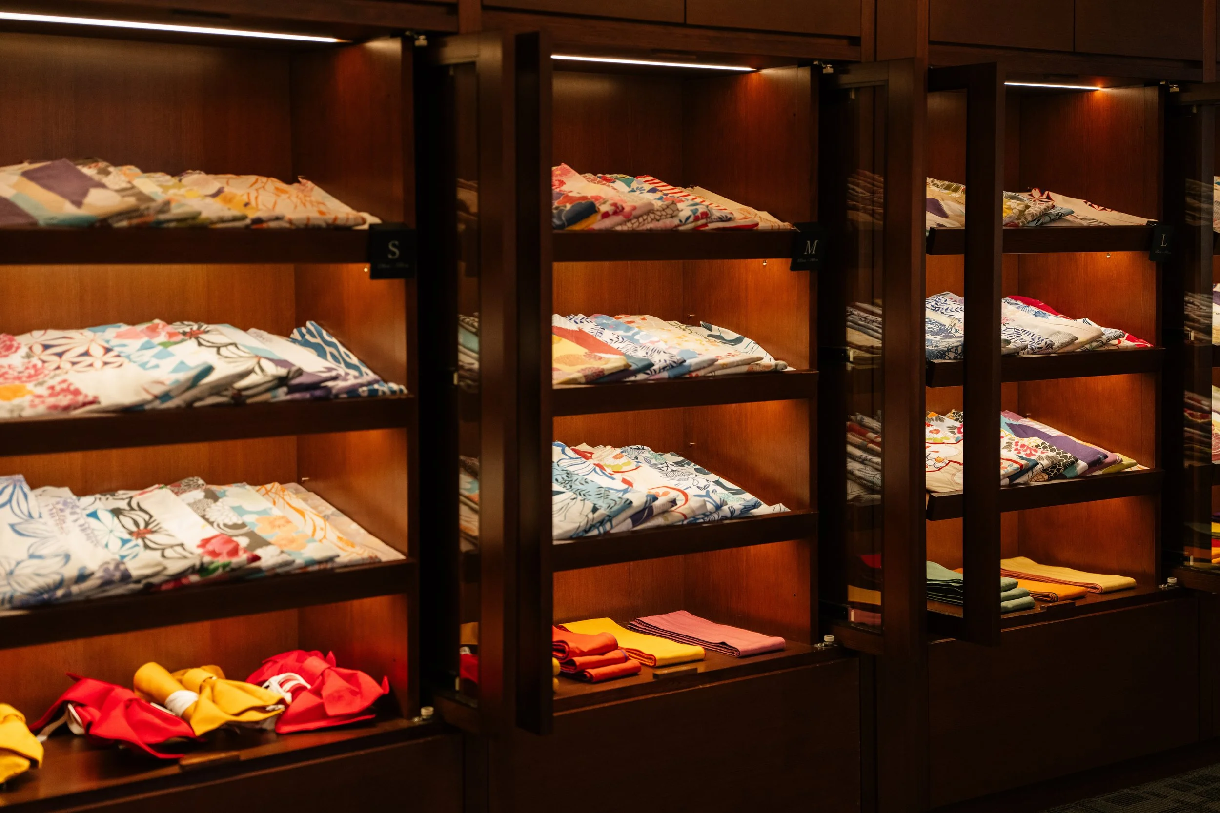 Display of neatly folded colorful fabric pieces and towels arranged on wooden shelves in a retail store.