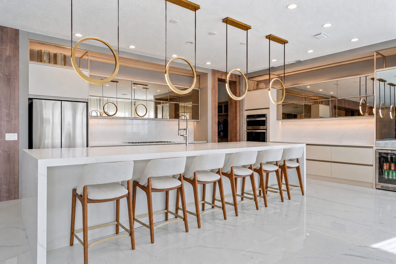 Modern kitchen design with a large marble island, custom cabinetry, gold pendant lighting and warm wood accents.