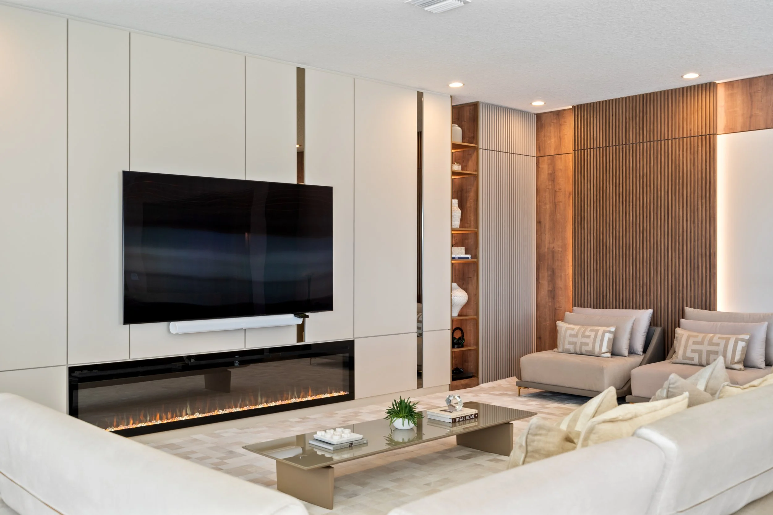 Modern living room interior with custom wall paneling, built-in fireplace, neutral furnishings and warm wood finishes.