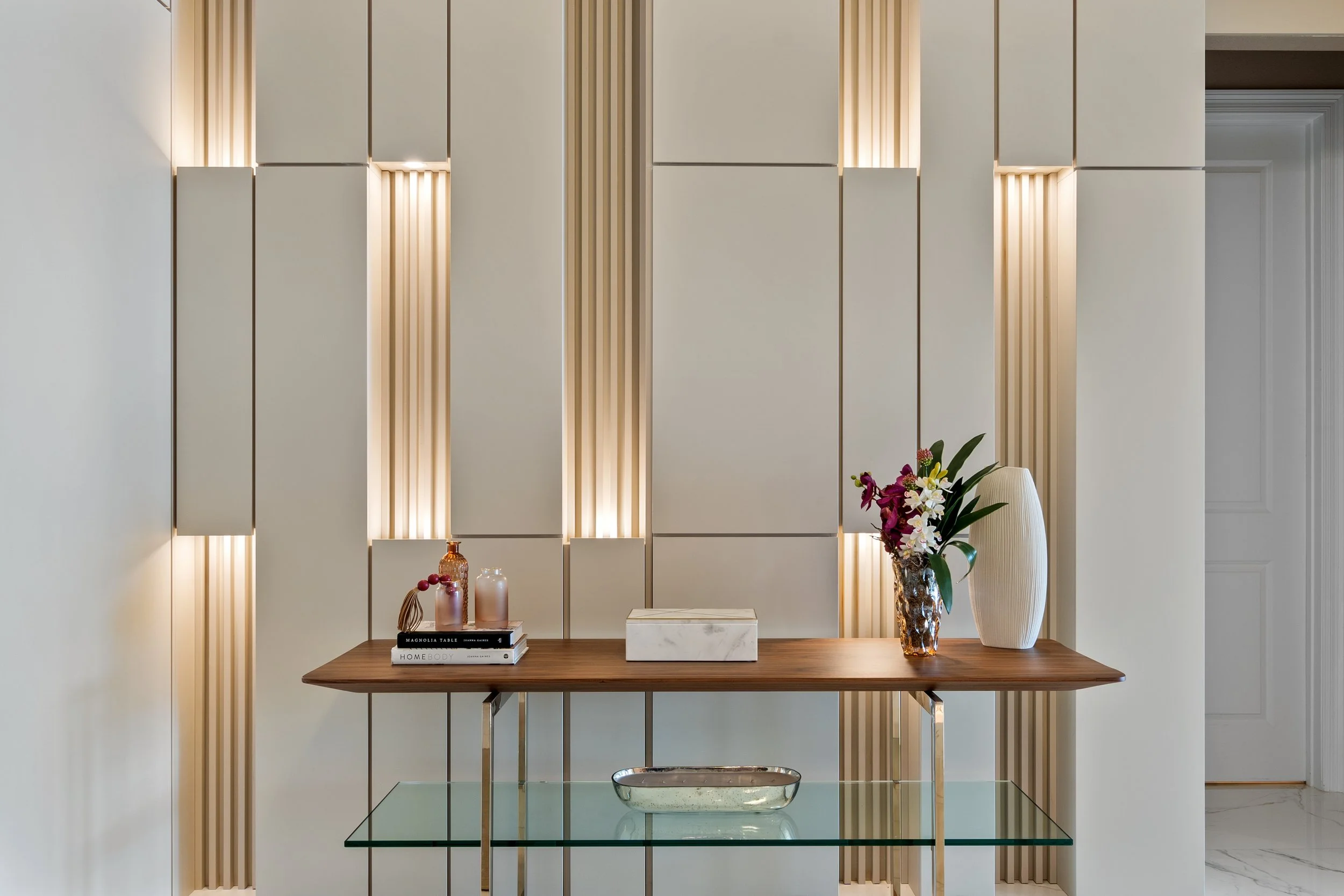 Custom interior wall design with warm wood slats, neutral panels and integrated lighting by Studio Bortto.