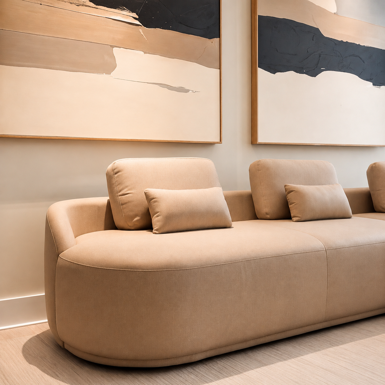 Contemporary living room detail with a curved beige sofa, neutral palette and abstract wall art.