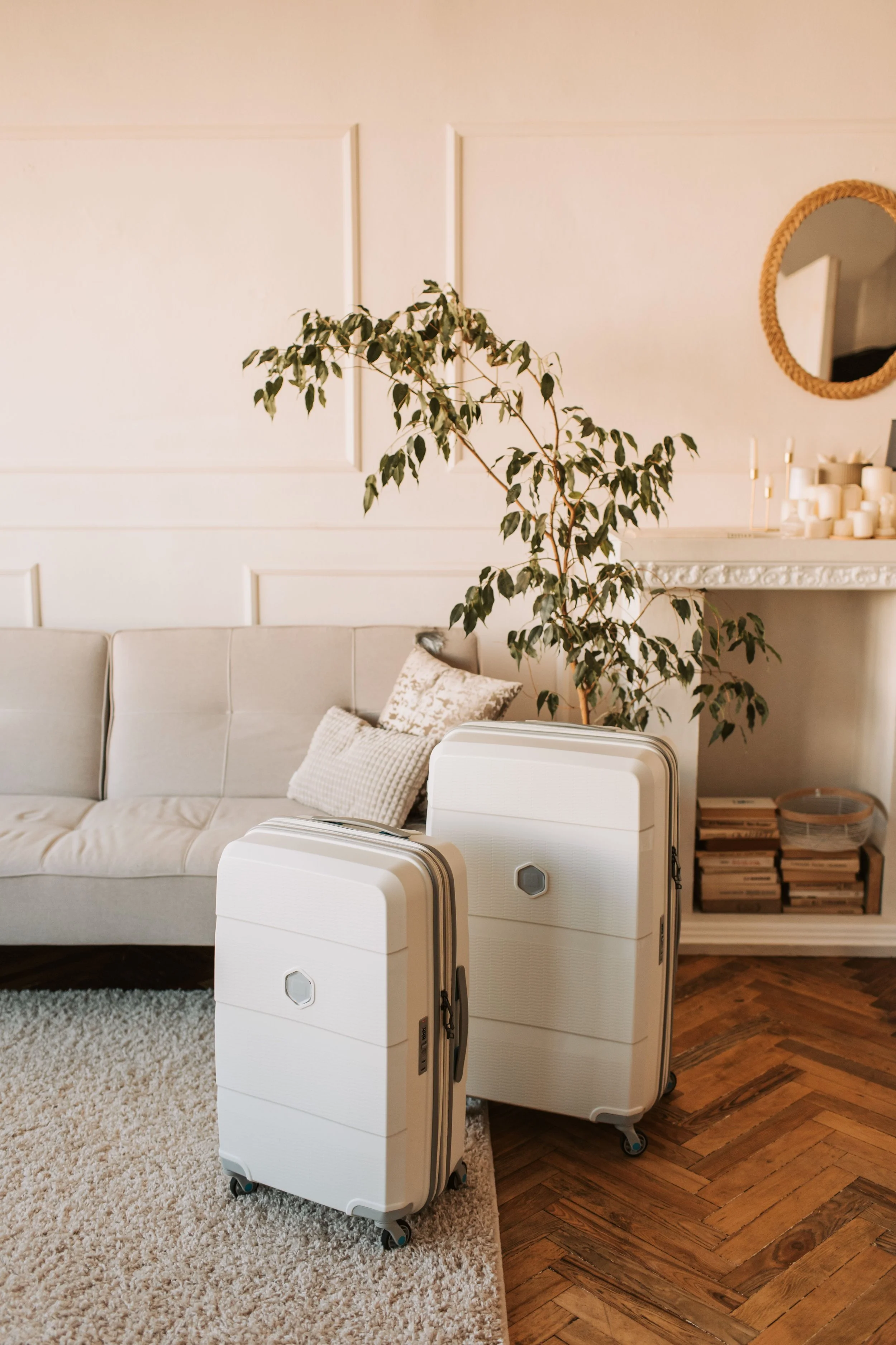 Living room with white sofa, beige pillows, potted plant, mirror, candles, and two white portable air purifiers.