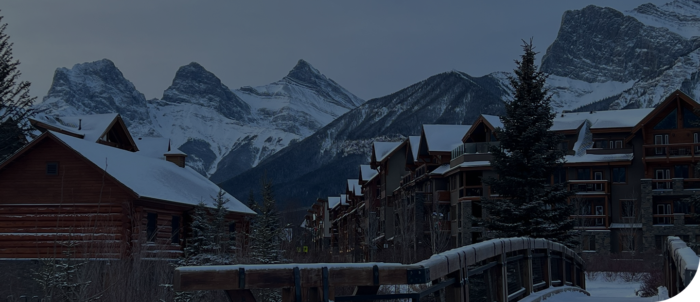 Snow-covered mountains, chalet-style buildings, and pine trees in a mountainous winter landscape