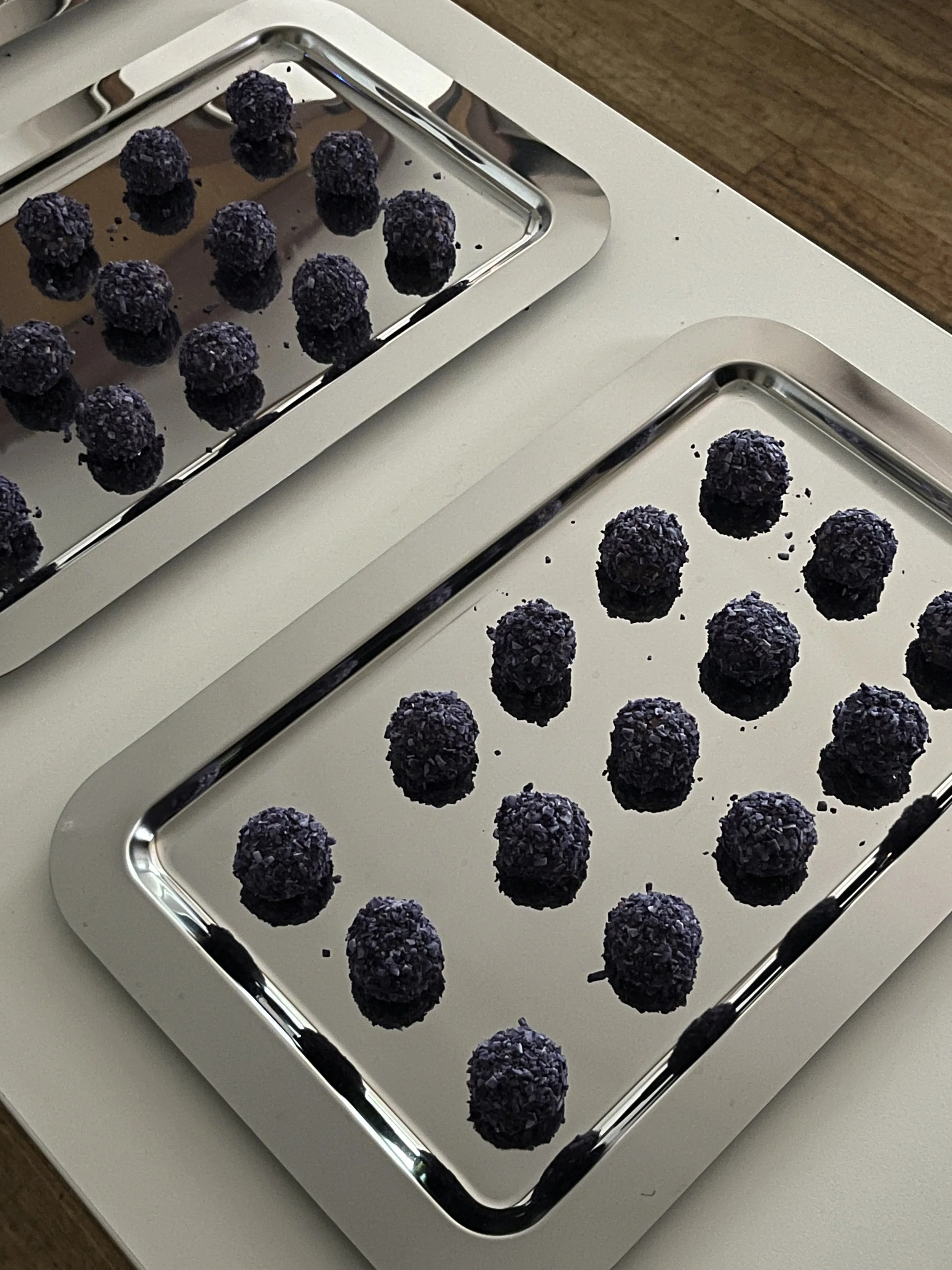Silver tray of organic lavender truffles on a white surface.