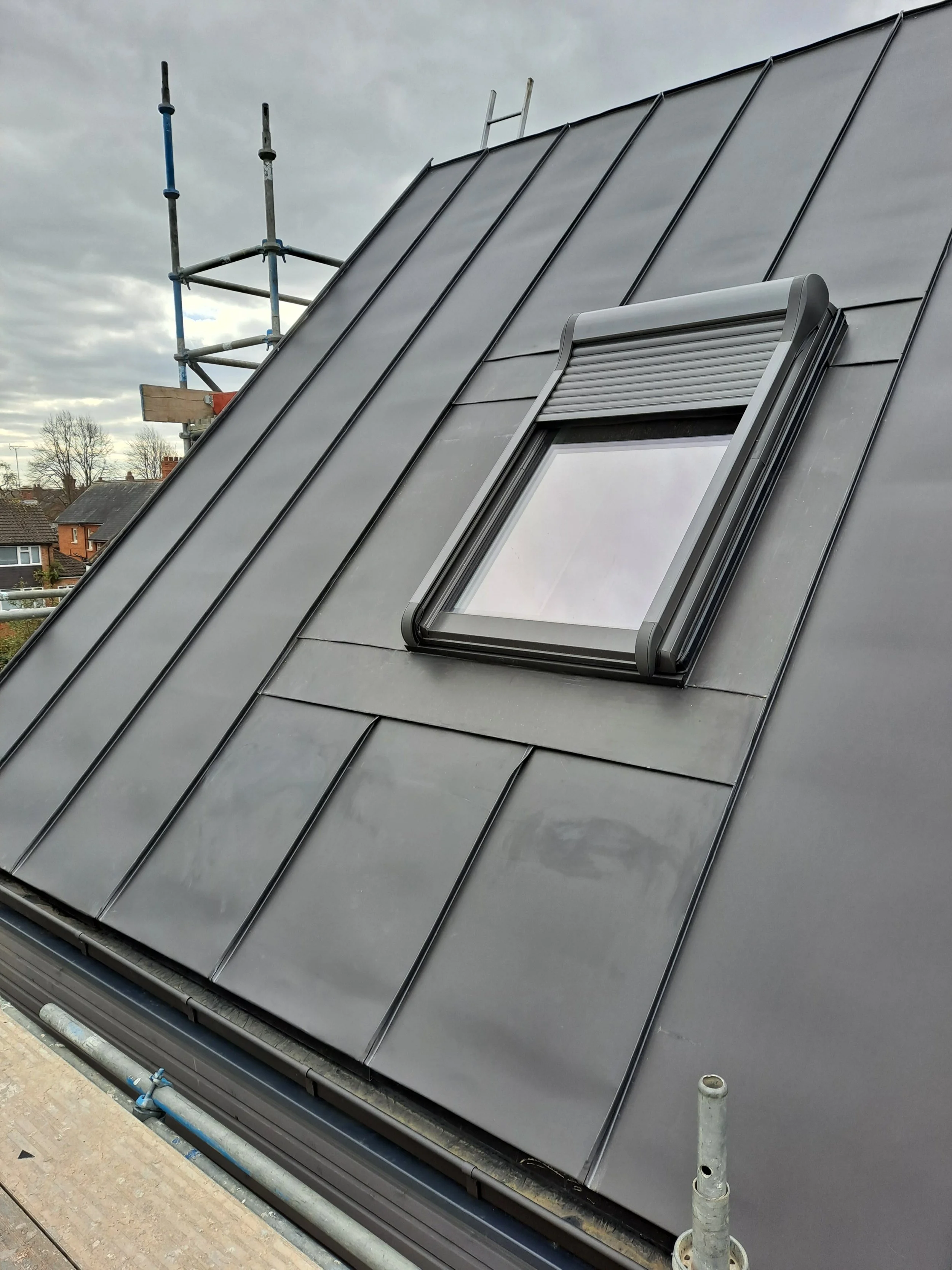 Close-up of a modern rooftop with metal panels and a skylight window.