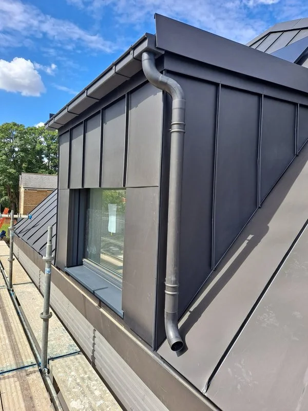 Close-up of VMZINC Anthra (standing seam) roof and façade cladding, modern house roof with gray metal panels.