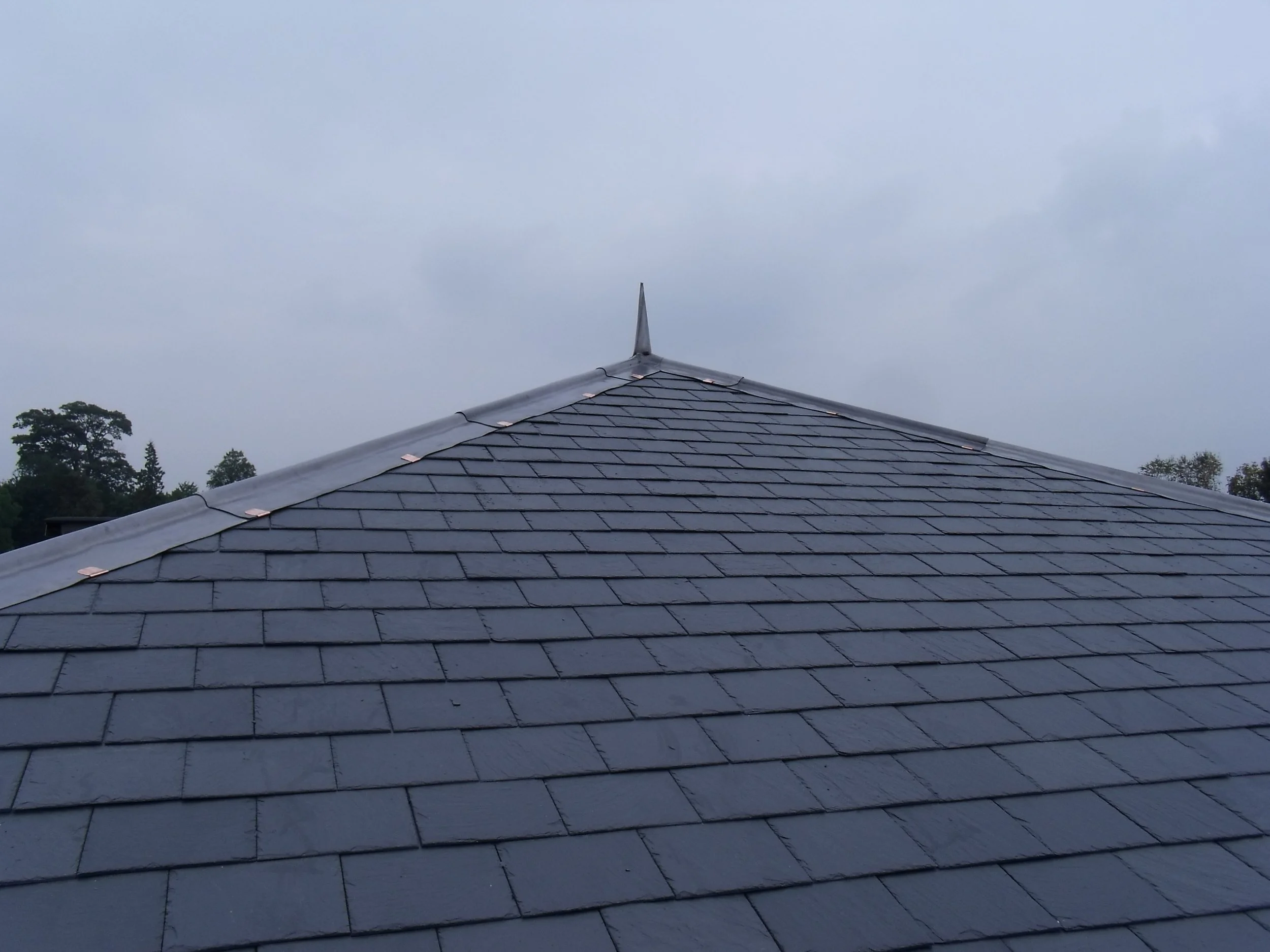 Rooftop with dark gray shingles and a decorative point at the center.