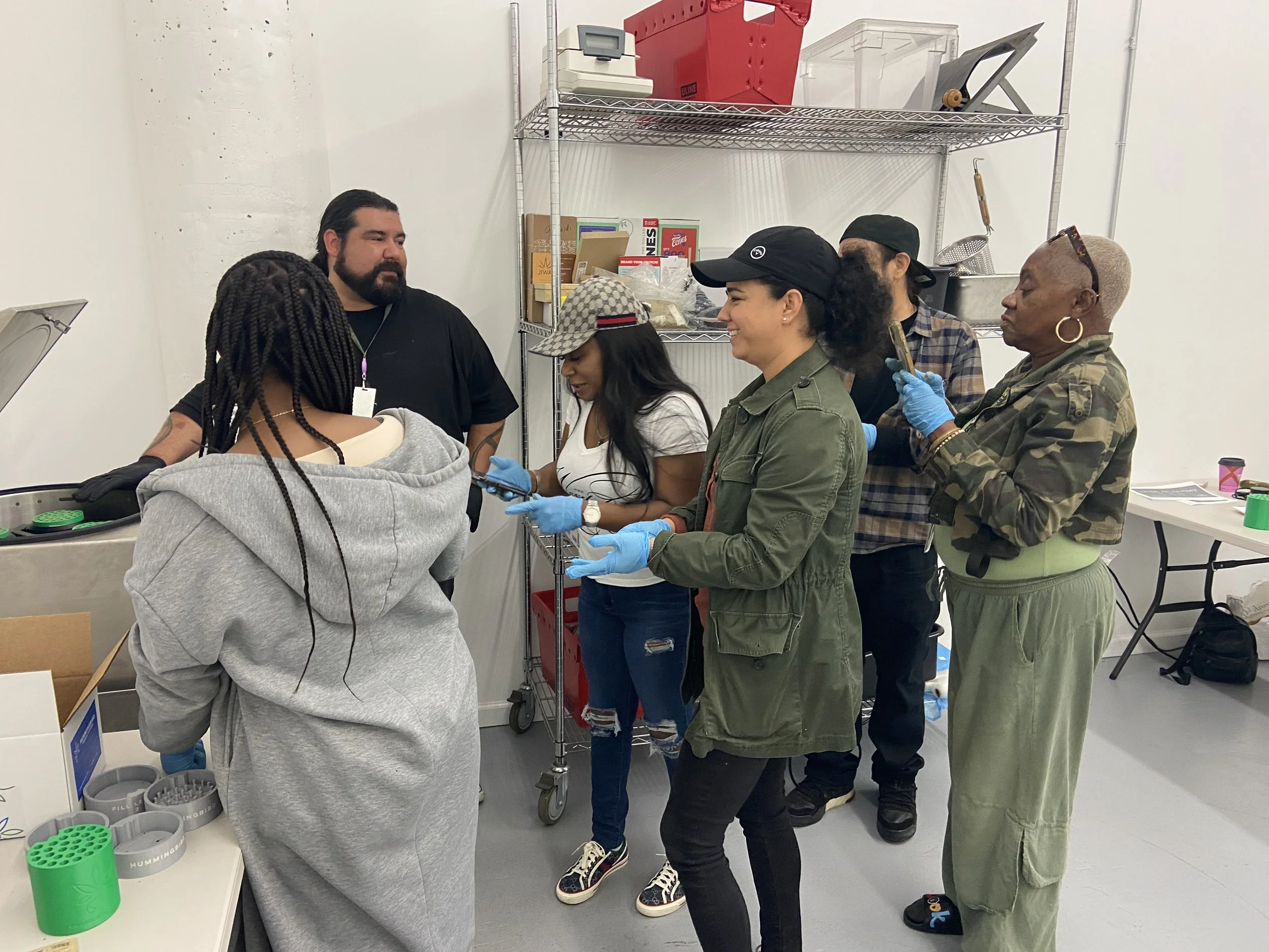 Doja Academy workshop participants gather around a worktable with Hummingbird pods.