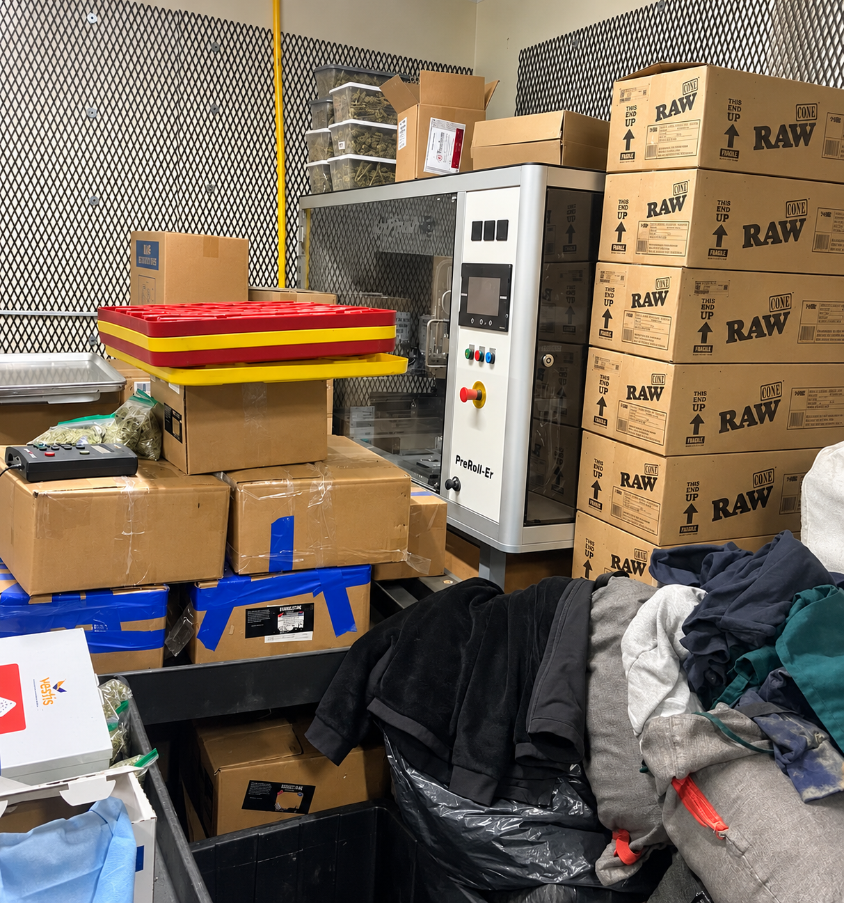 BoxFinisher preroll equipment sitting off-line in a cluttered production and storage area