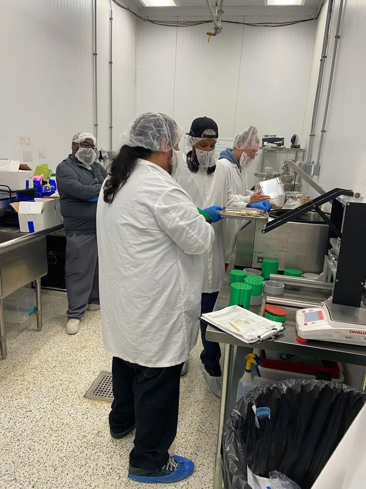 Staff in protective clothing gather around a Hummingbird equipment demonstration.