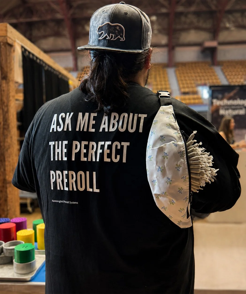 Aaron from Hummingbird Preroll Systems wearing an Ask Me About the Perfect Preroll shirt at a cannabis industry event