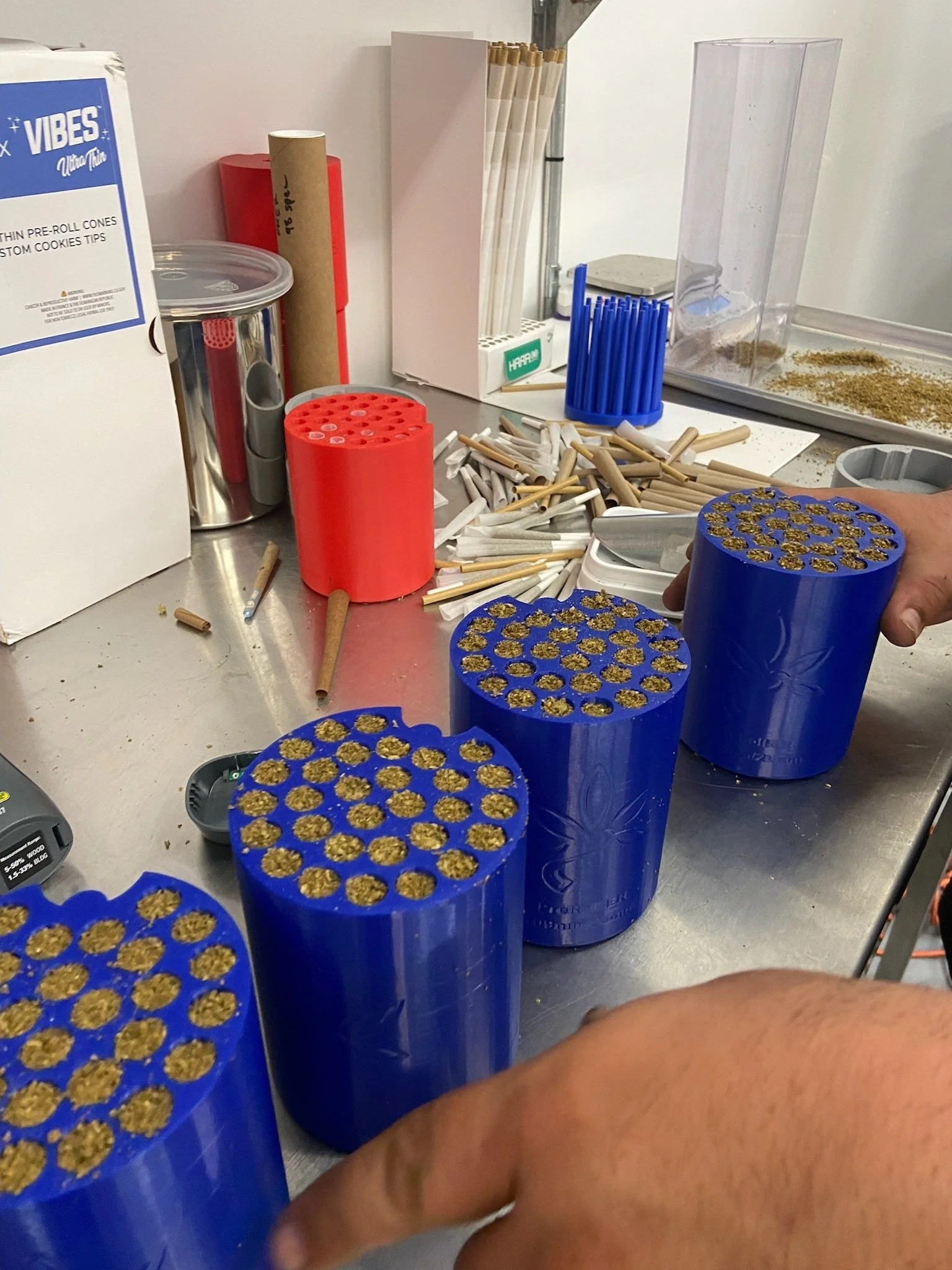 Several blue Hummingbird pods holding filled cones on a production worktable.