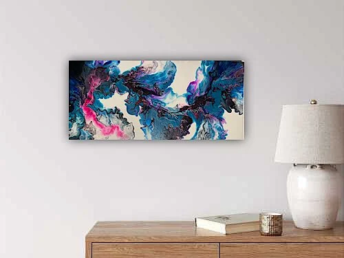 Abstract wall art with blue, pink, and black swirling patterns hanging above a wooden console table with a book and decorative jar, near a white lamp with a beige shade.