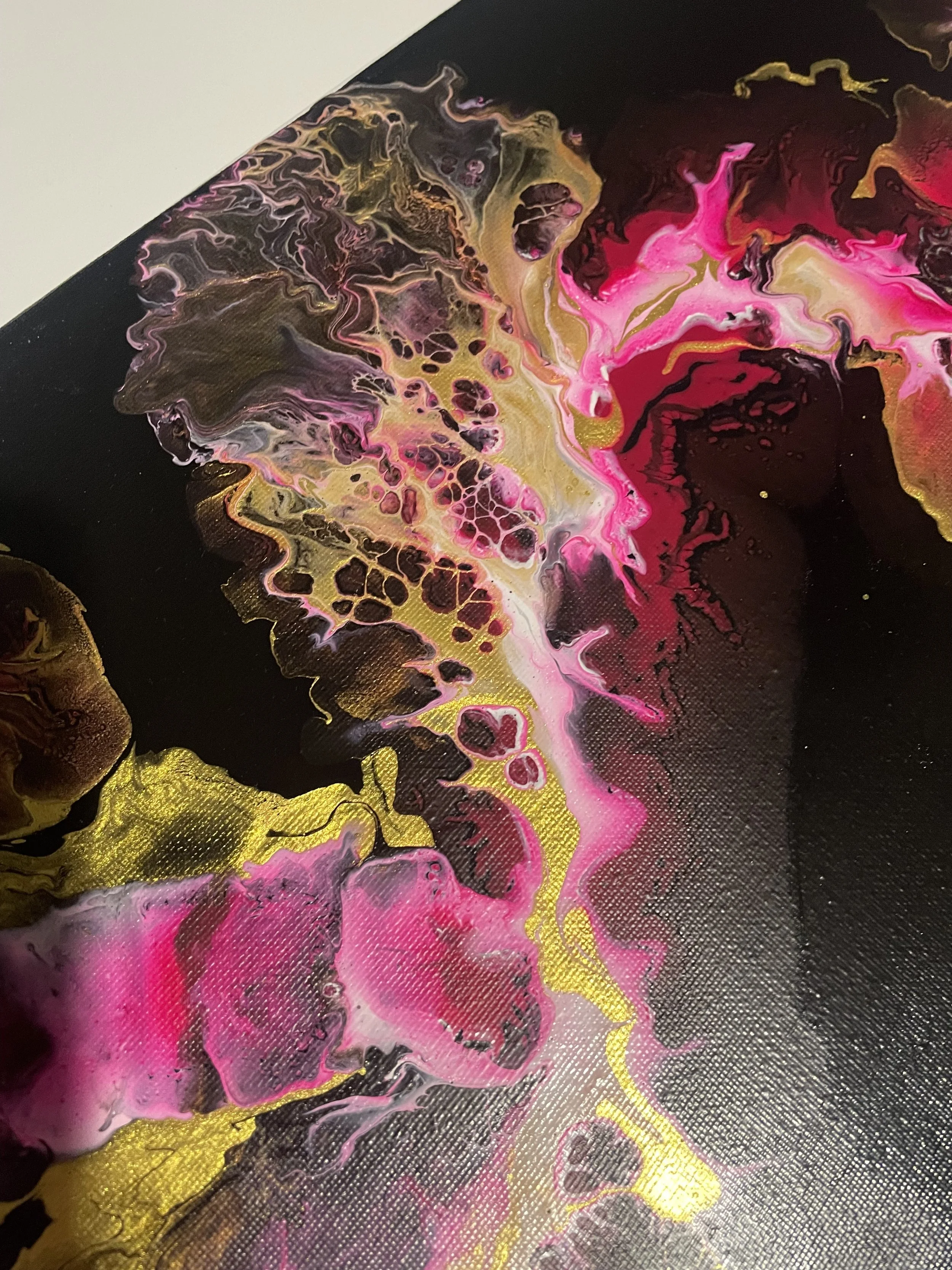 Abstract acrylic painting with swirling pink, gold, black, and white colors.