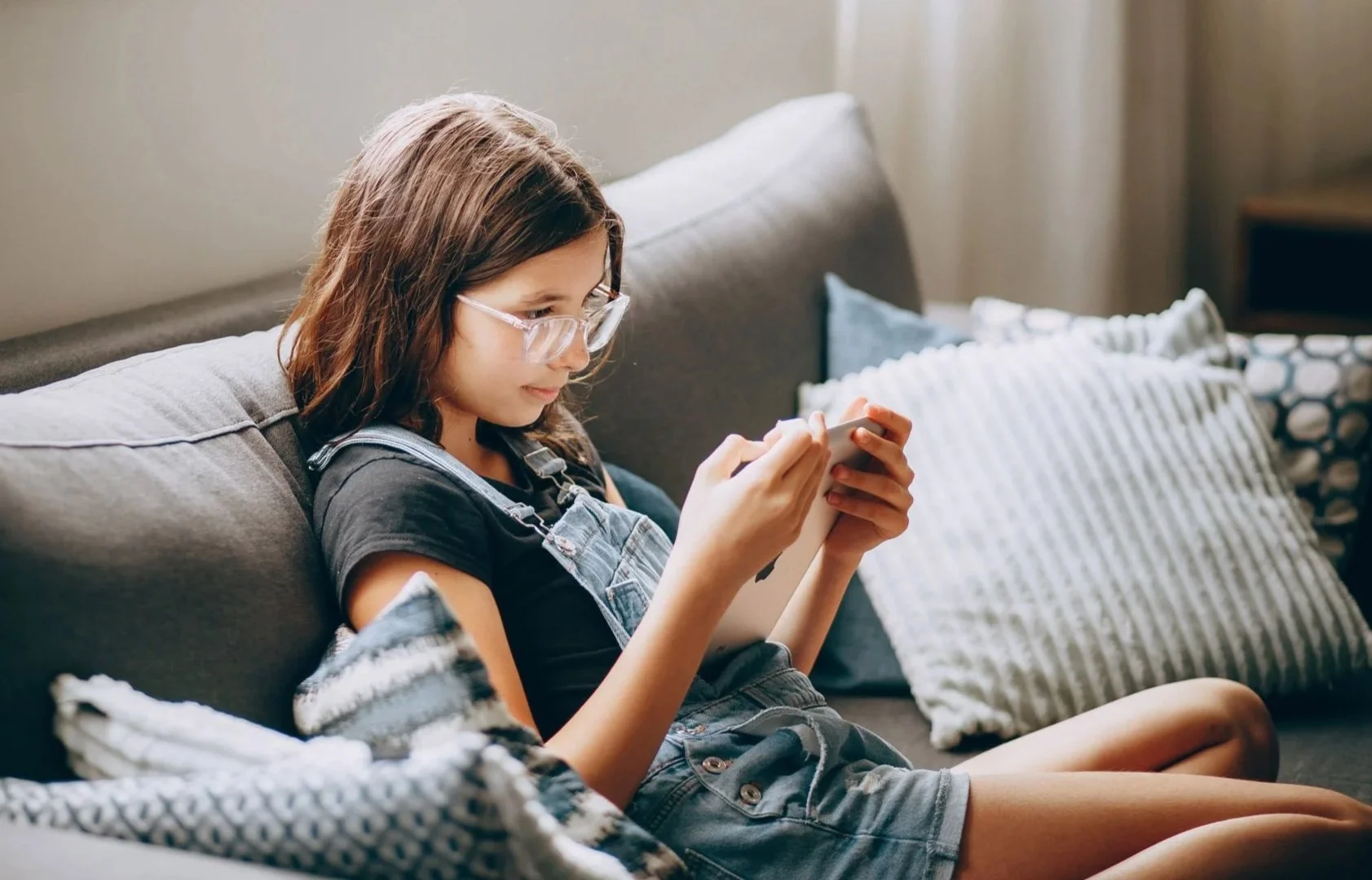 oung girl relaxing on a couch while using an iPAD