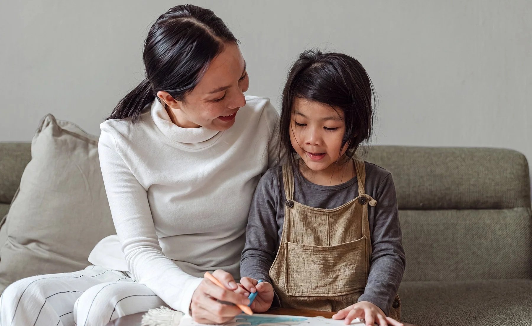 Mother helping her young daughter with a drawing at the table