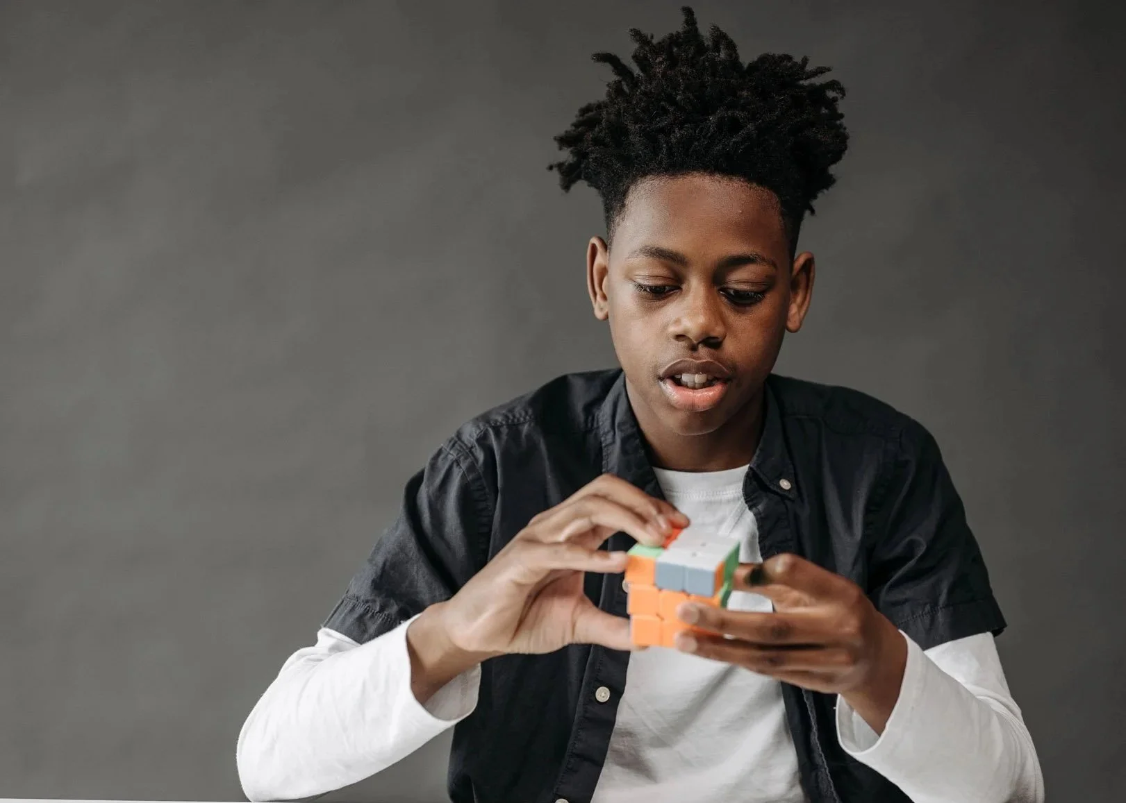 Teenage boy concentrating while solving a Rubik's cube