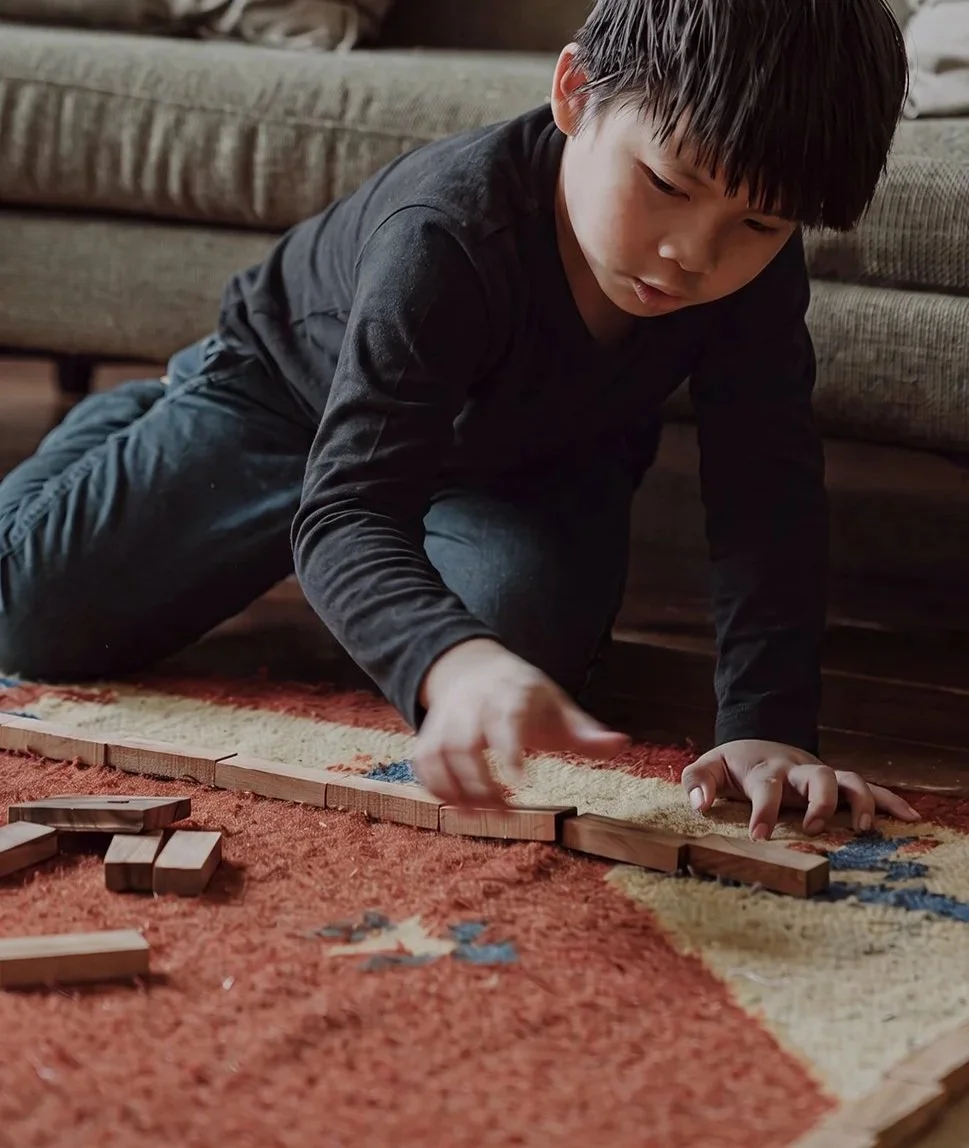 Young boy playing with wooden block toys on a rug