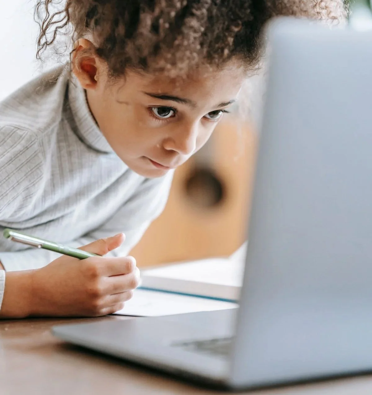 Child concentrating while doing homework on a laptop