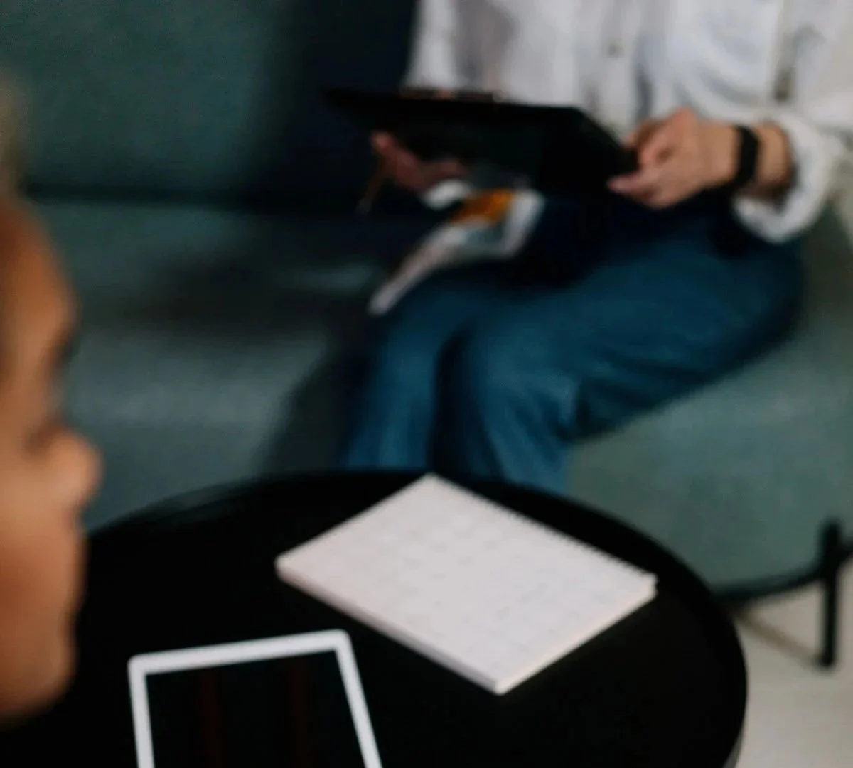 Person reviewing documents and a tablet at a coffee table