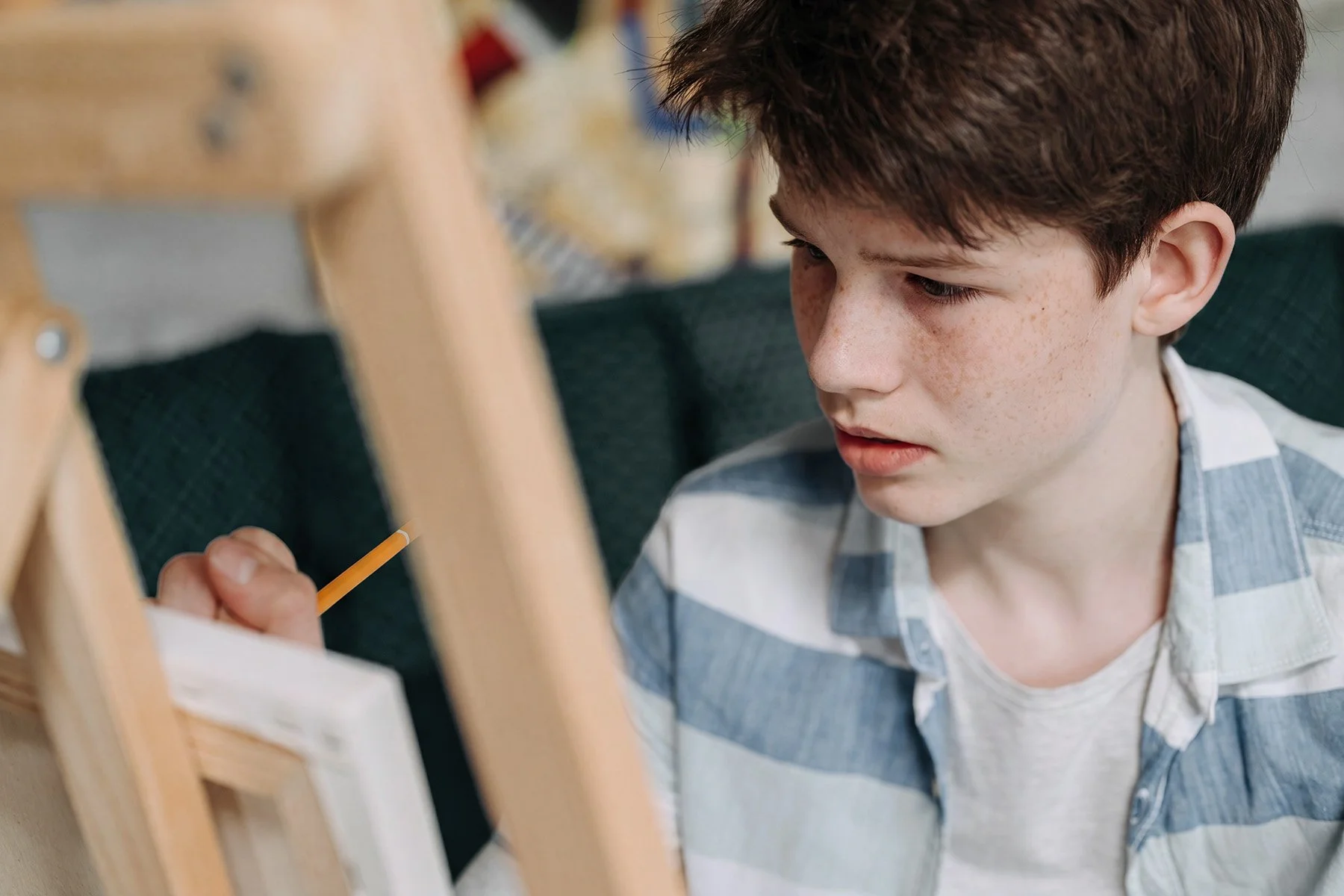 Young boy focused on drawing at an easel