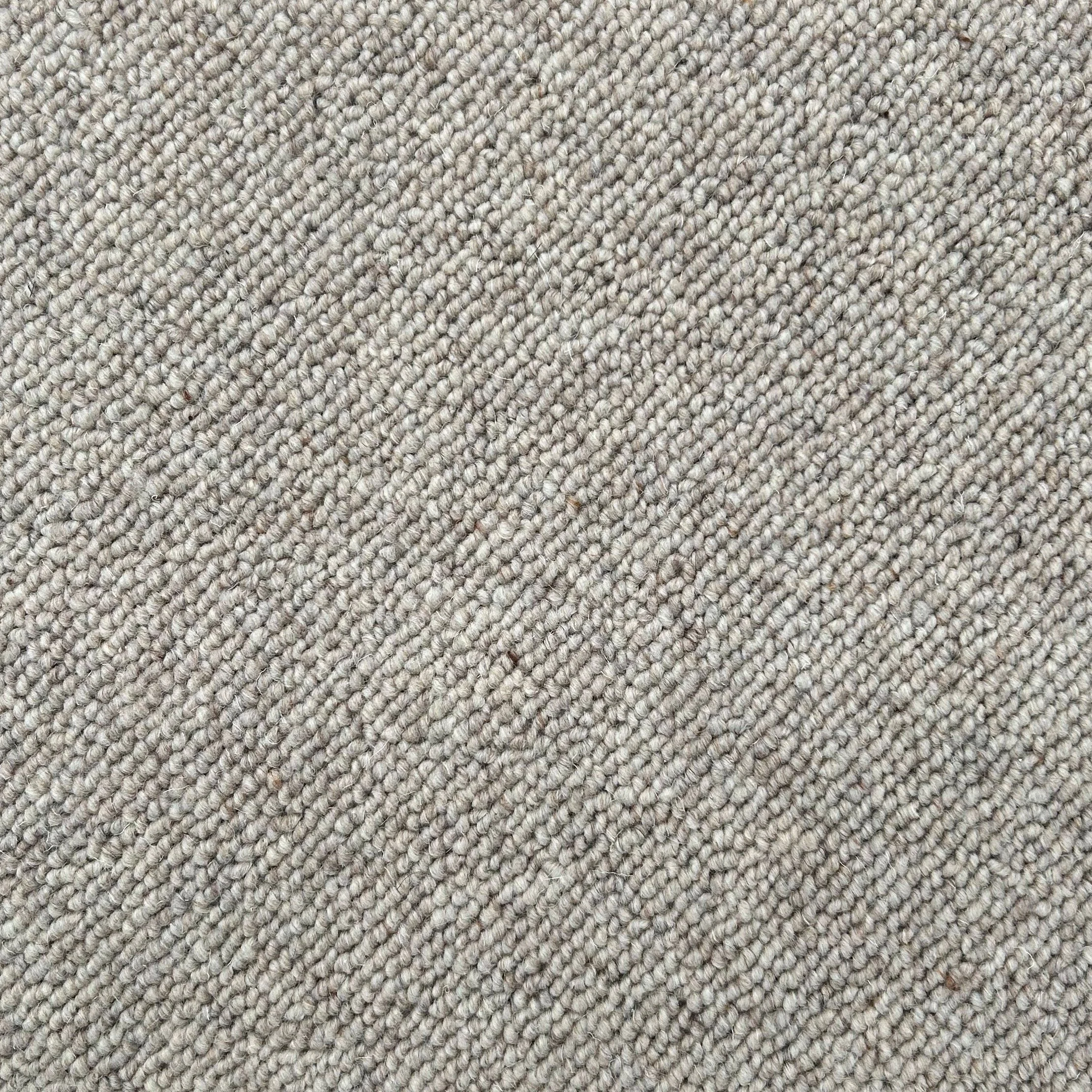 Close-up view of a textured beige carpet with tightly woven fibers.