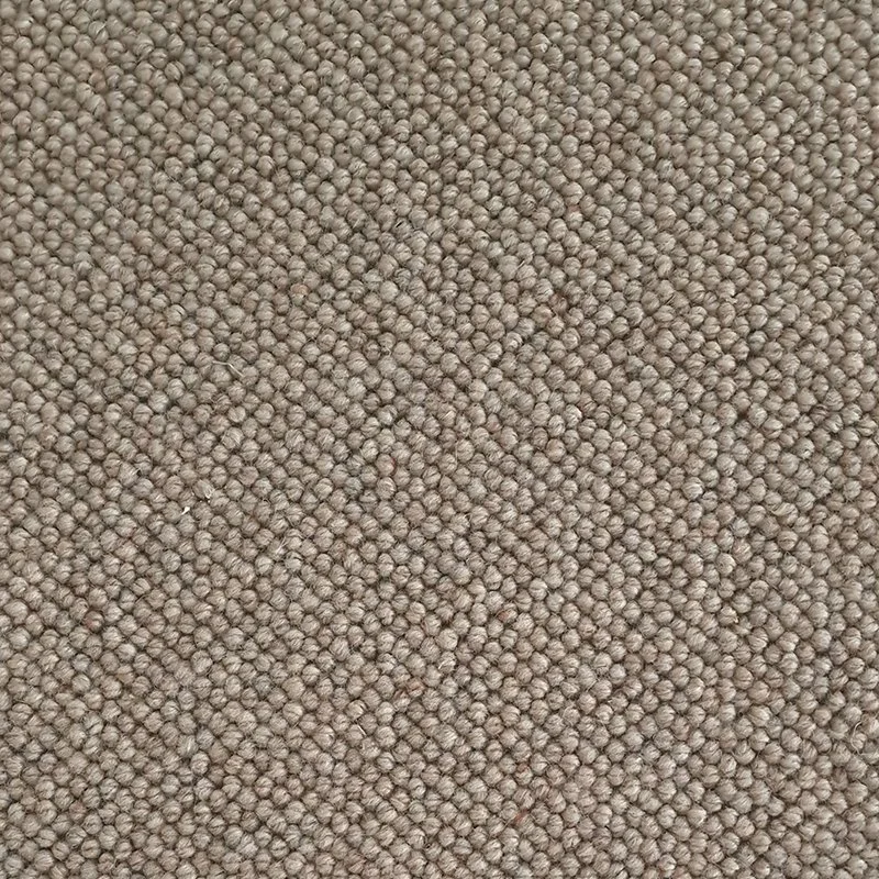 Close-up of a textured beige carpet with small, tightly packed fibers.