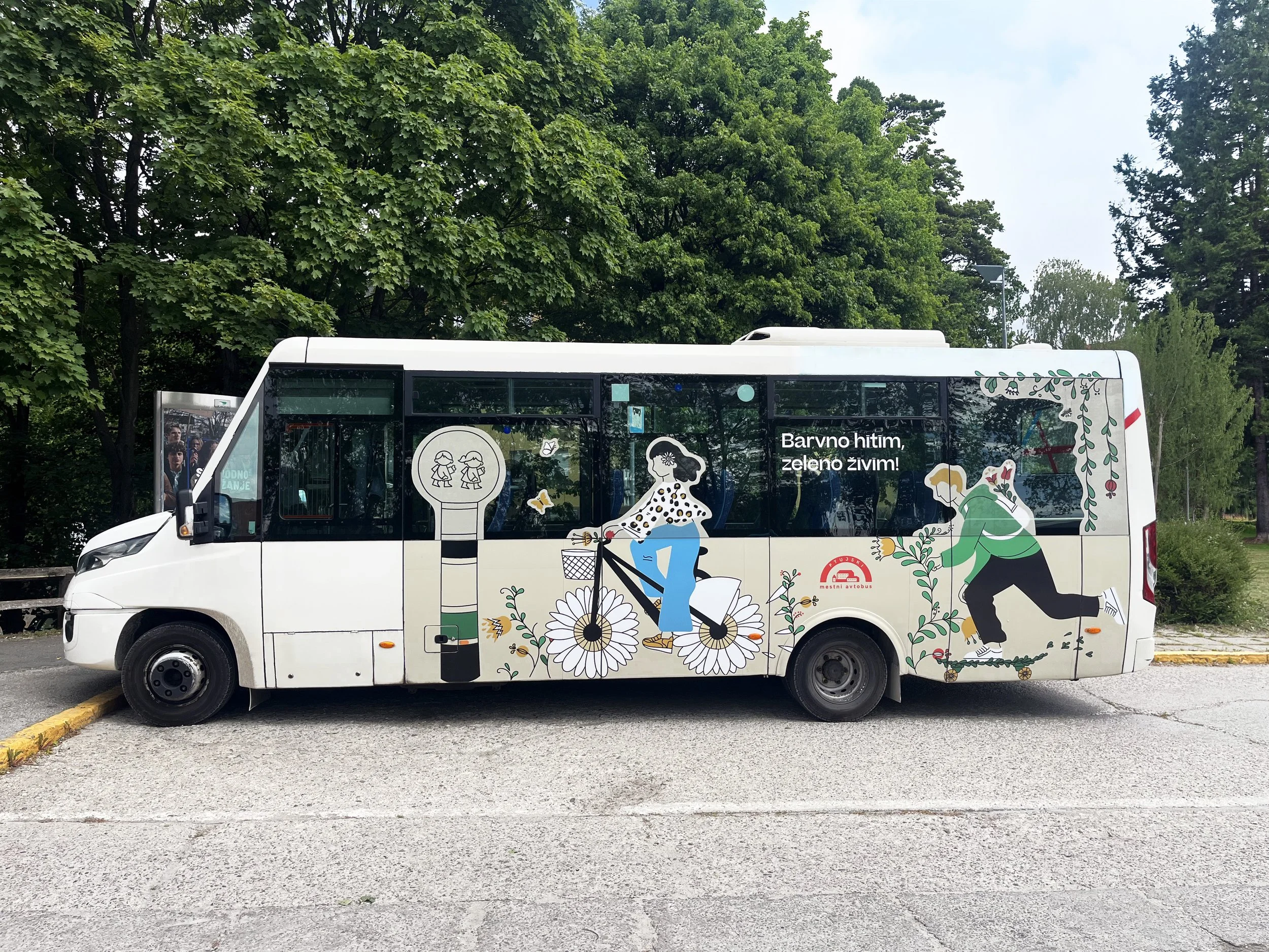 A white electric bus with the 10m  long colouring sheet, "Safe to School, Travel Sustainably!" Communication campaign was developed as part of the CityWalk 2.0 Ptuj project to promote sustainable ways of travelling to school..