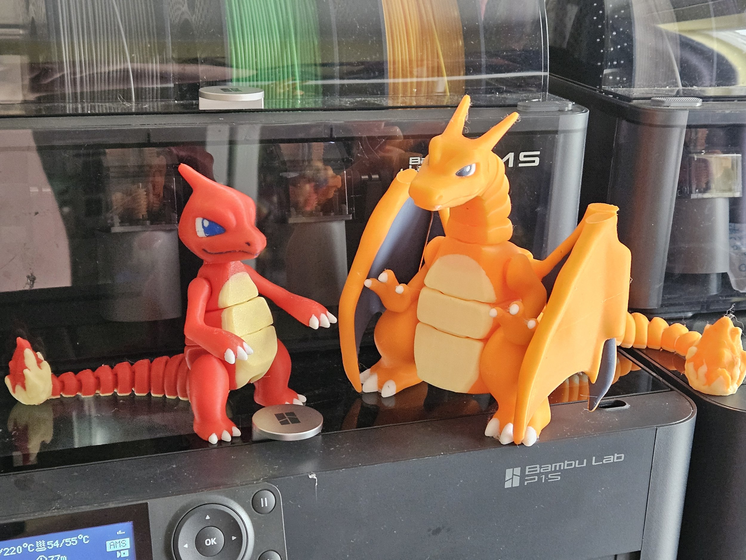 A collection of Pokémon figurines including Charizard and Salamence displayed on a black surface in front of a glass cabinet with various ink pens in different colors.