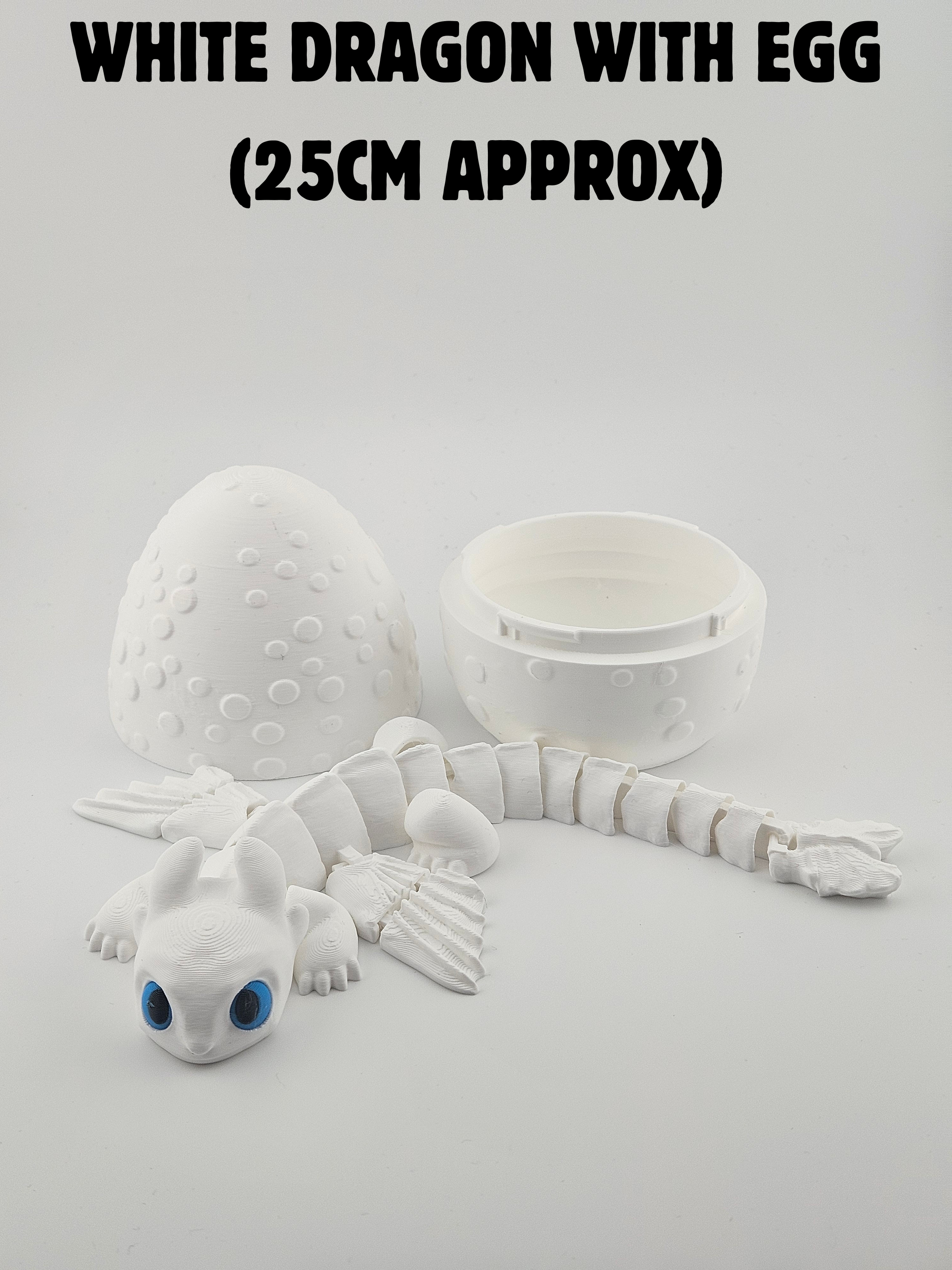 A white plastic dragon model with big blue eyes, a segmented tail, and textured body parts, along with two white egg-shaped objects and an open container, all set against a plain white background.