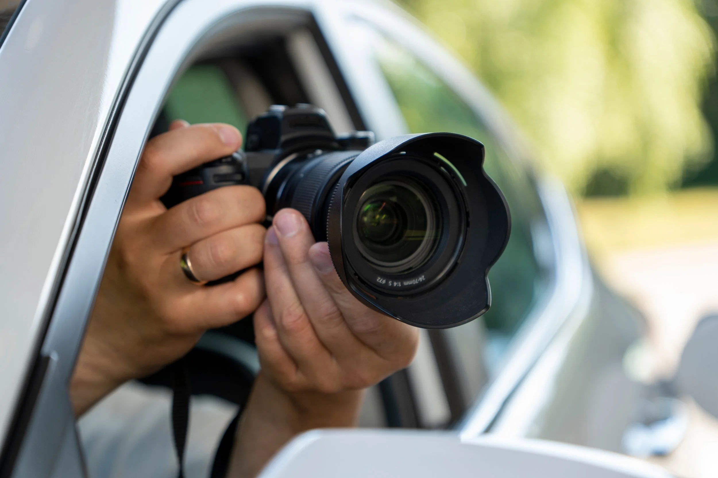 A person using a camera to take a picture of a car's side mirror from outside the vehicle.