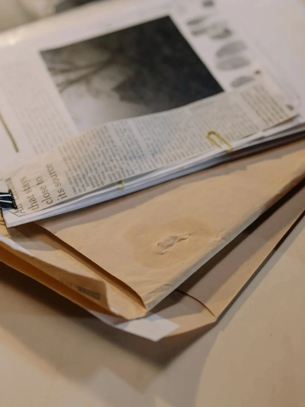 An open newspaper resting on a paper bag placed on a table.