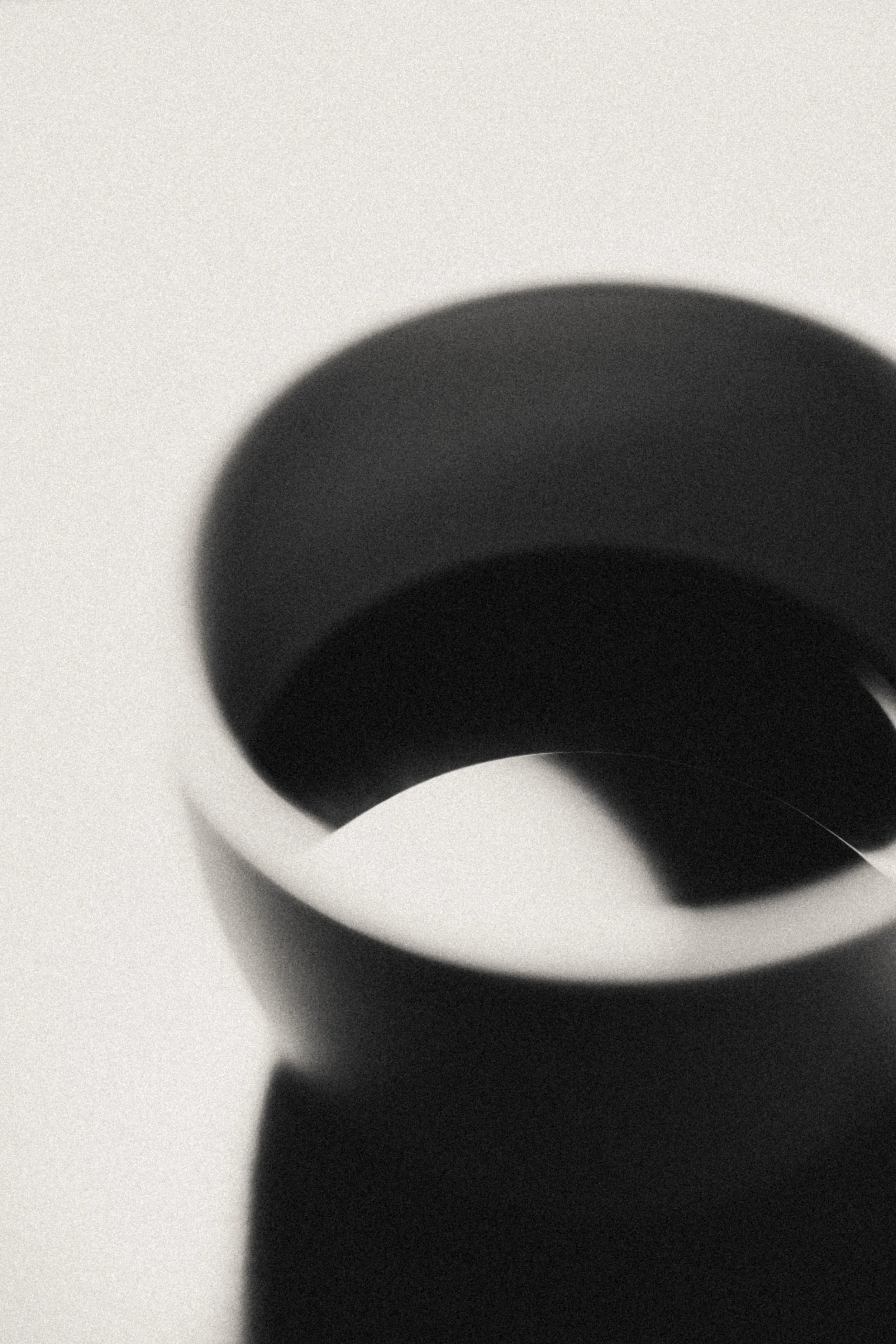 Close-up of a black shadow on a white surface, creating a circular shape with subtle gradient variations.