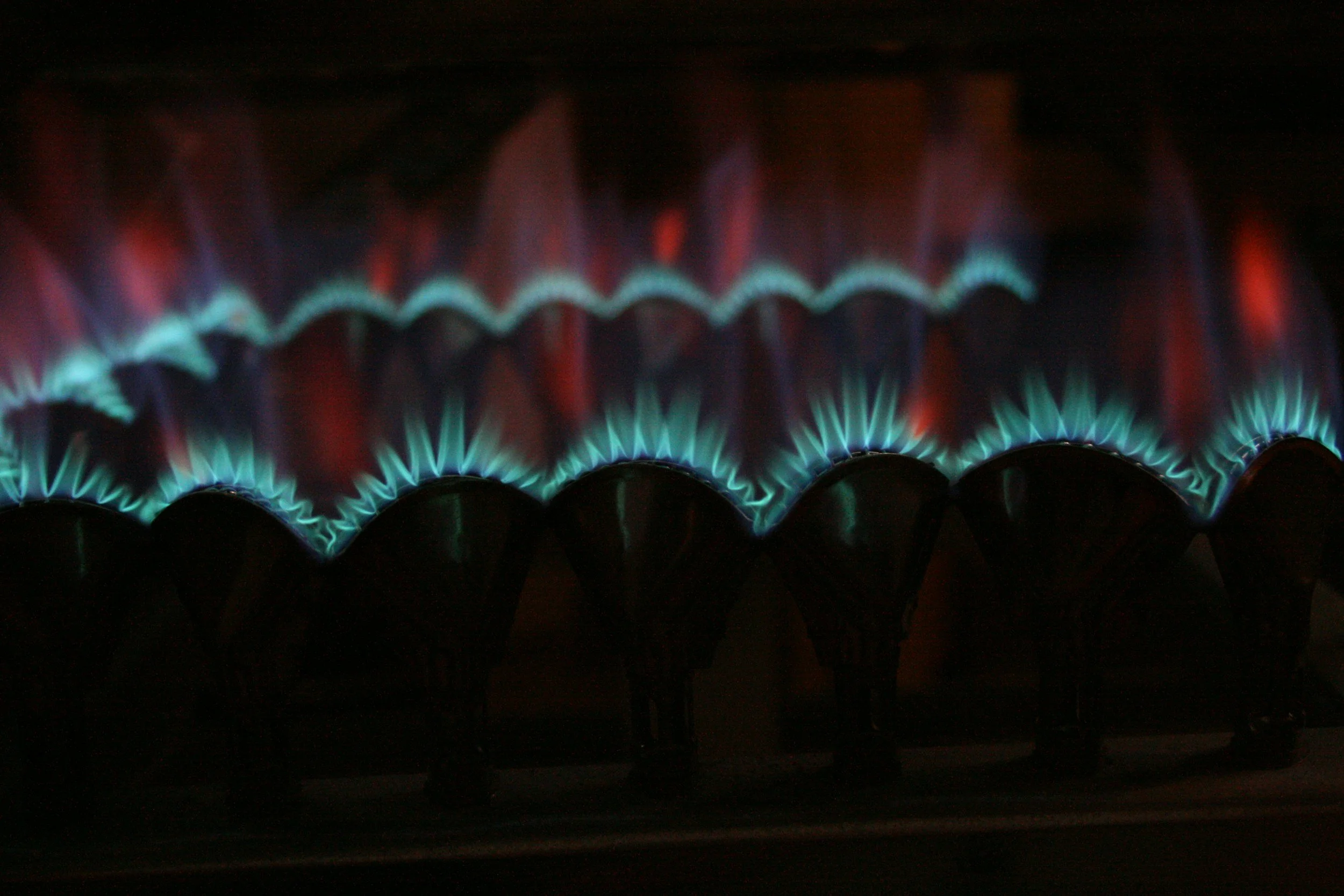 Blue and red flames from gas burners on a stovetop.