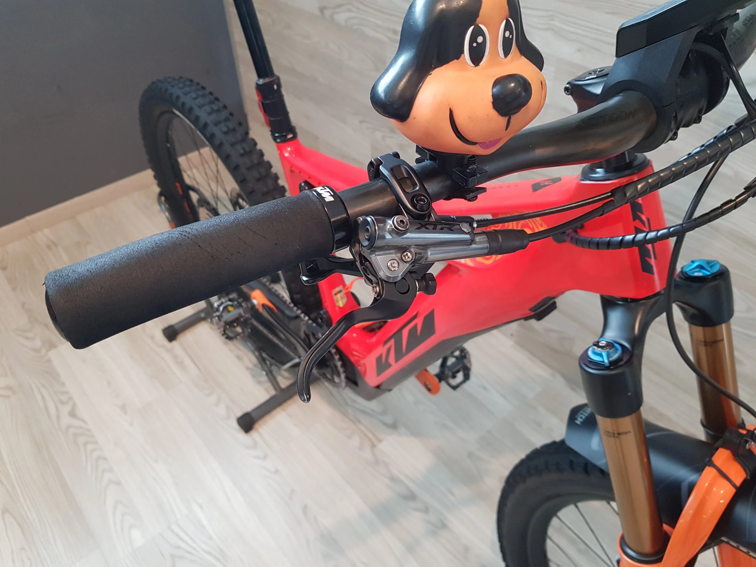 Una bicicletta rossa con un manubrio nero, gomme grandi e una testa di pupazzo di Snoopy come decorazione sulla manopola del manubrio.